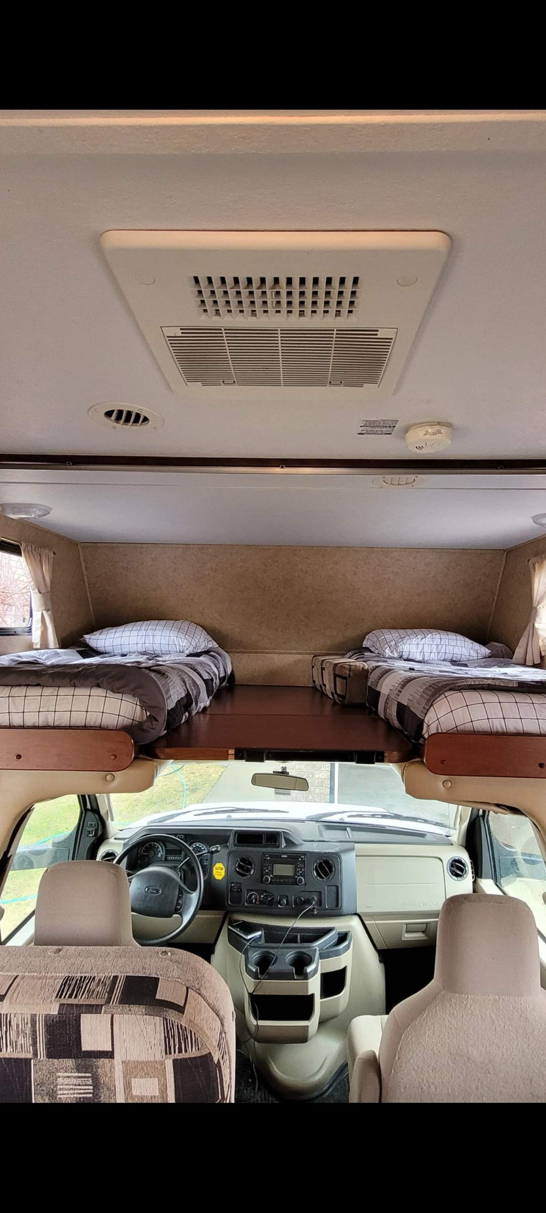 RV rental interior with cozy overhead bunk beds for travel, showcasing the driver's cockpit below.. Forester Forester Motorhome 2011