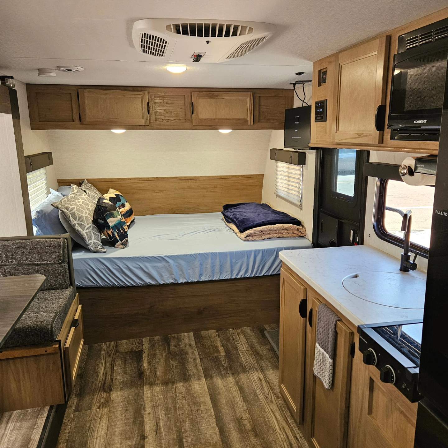 Cozy RV rental interior with a bed, dinette, and fully equipped kitchen, ideal for road trip comfort.. Forest River Cherokee Wolf Pup 17JW 2024