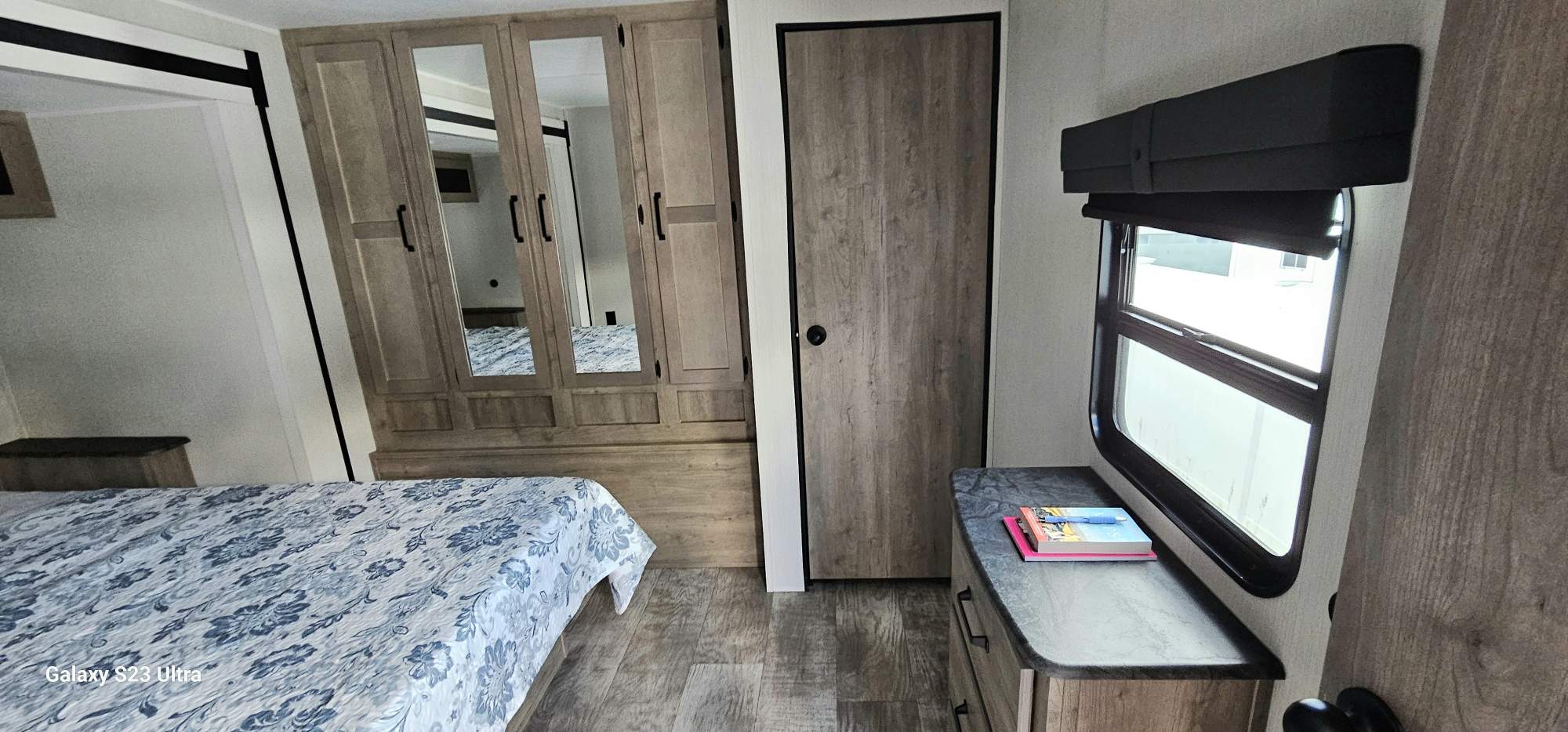 RV rental bedroom with patterned bedding, mirrored wardrobe, private door, and window. Your mobile comfort awaits.. Forest River Palomino Puma 2024