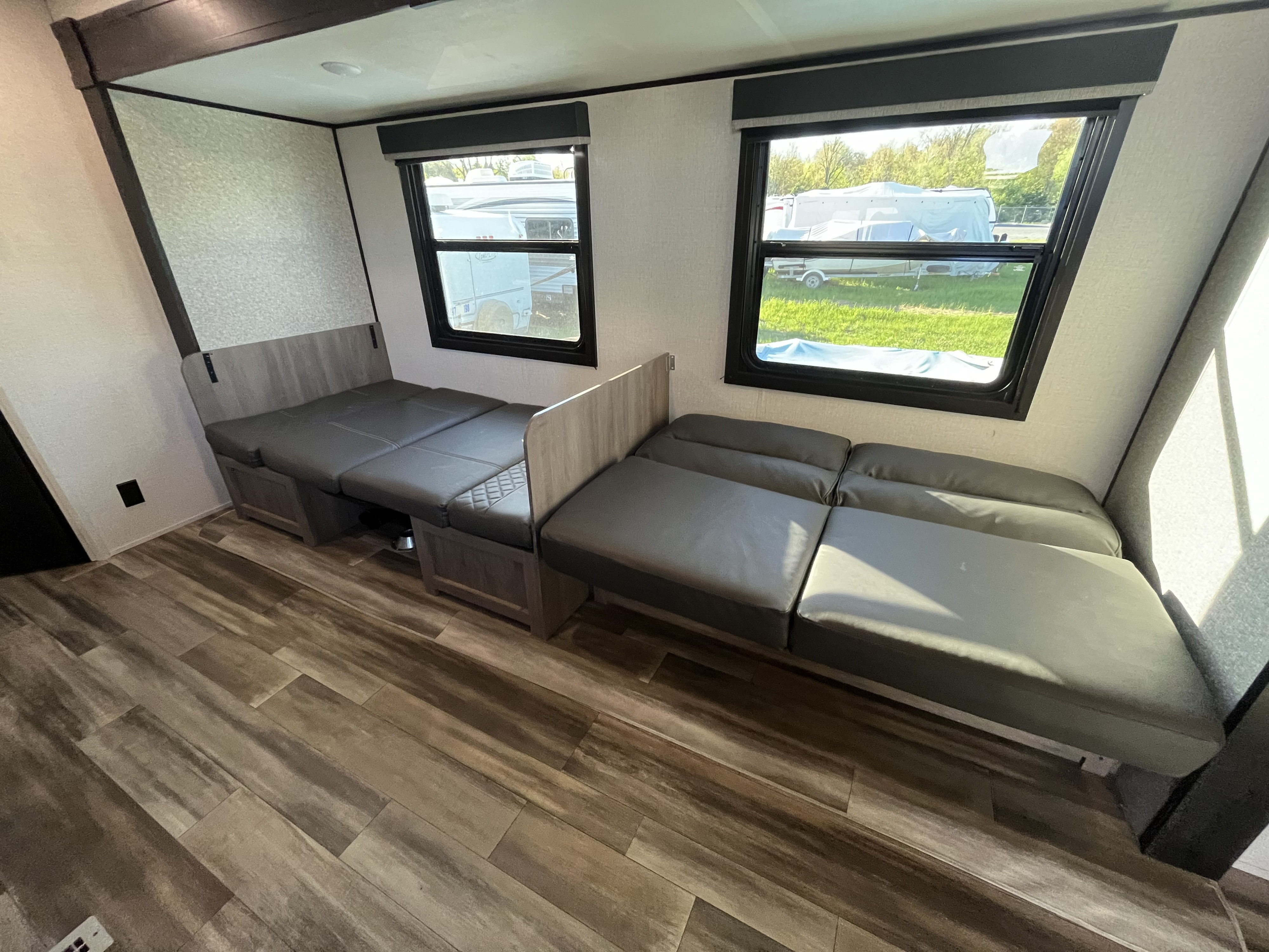Spacious RV rental interior featuring convertible seating/beds, large windows, and attractive wood-look flooring for comfort.. Starcraft Autumn Ridge 2022