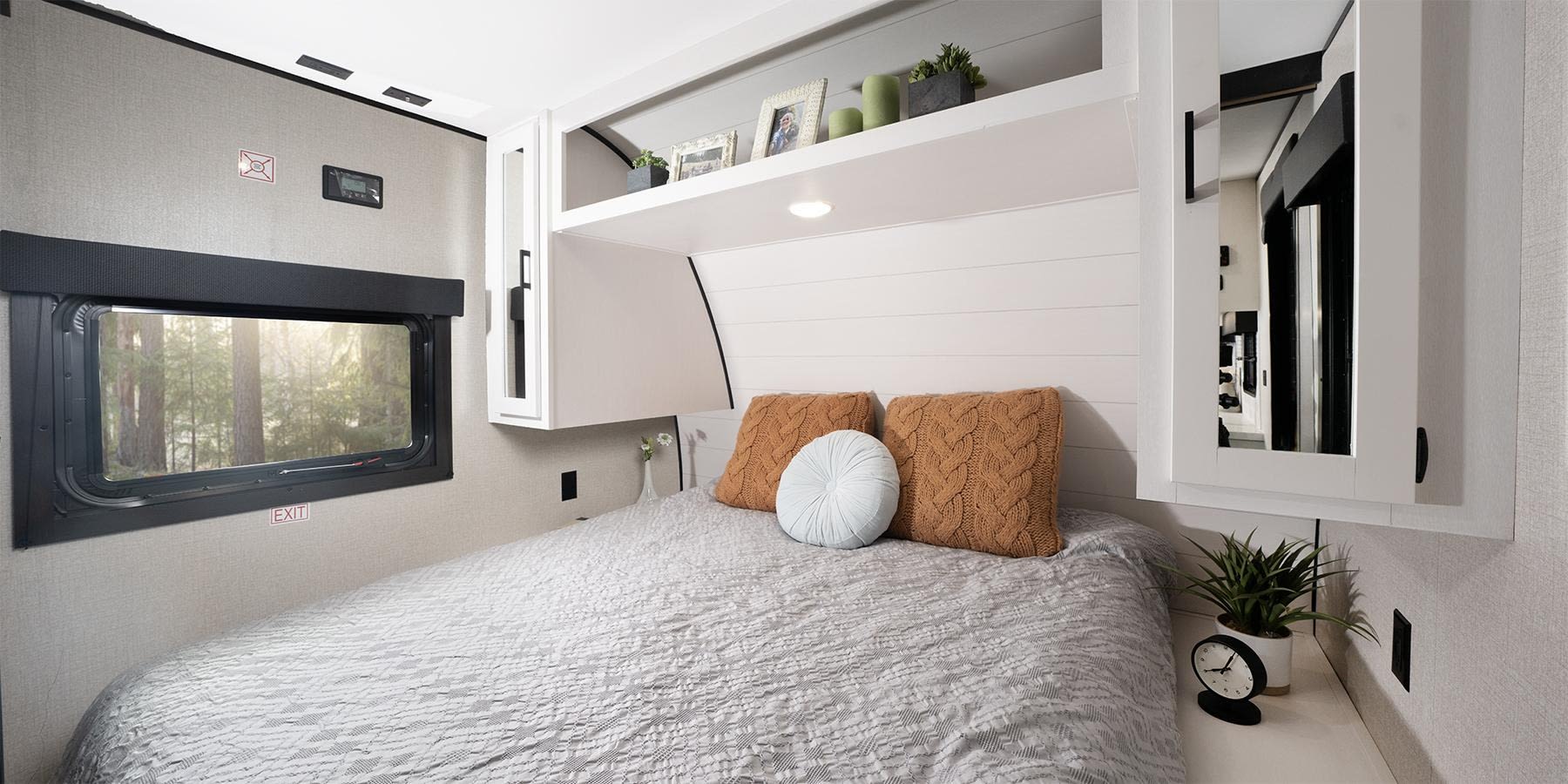 Cozy RV rental bedroom with comfortable bed, overhead storage, and forest views for your next adventure.. Highland Ridge RV Open Range 2024