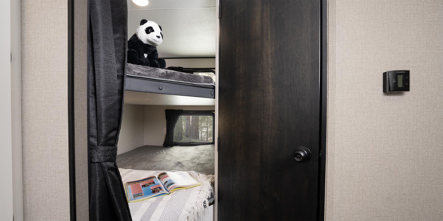 Inside an RV rental: comfy bunk beds with a panda, forest view, and a Dometic thermostat, ready for travel adventures.. Highland Ridge RV Open Range 2024