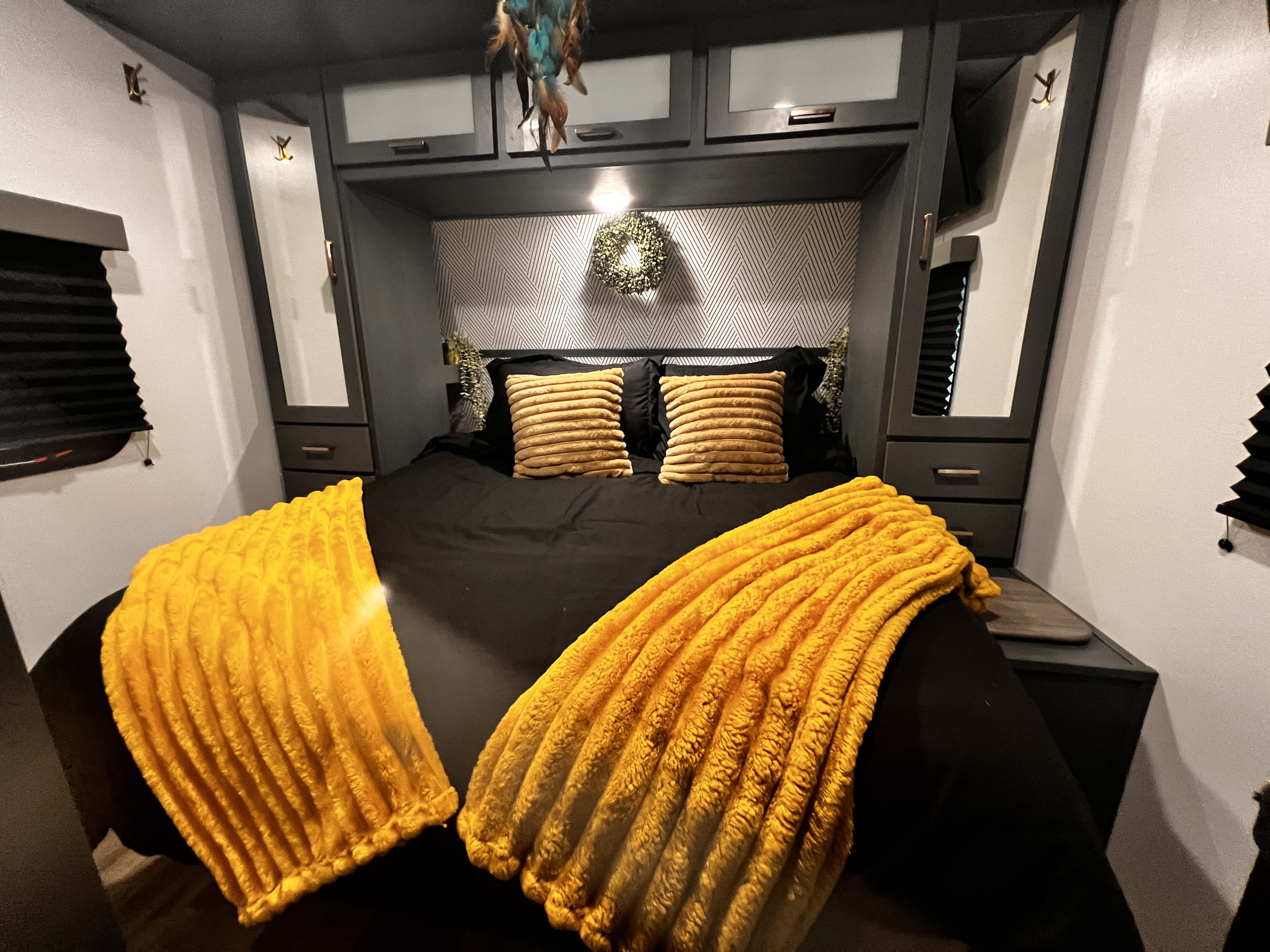 Inviting RV rental bedroom with a modern aesthetic, comfy black bed, and warm yellow throws for a cozy stay.. Keystone RV Bullet Ultra Lite 2022