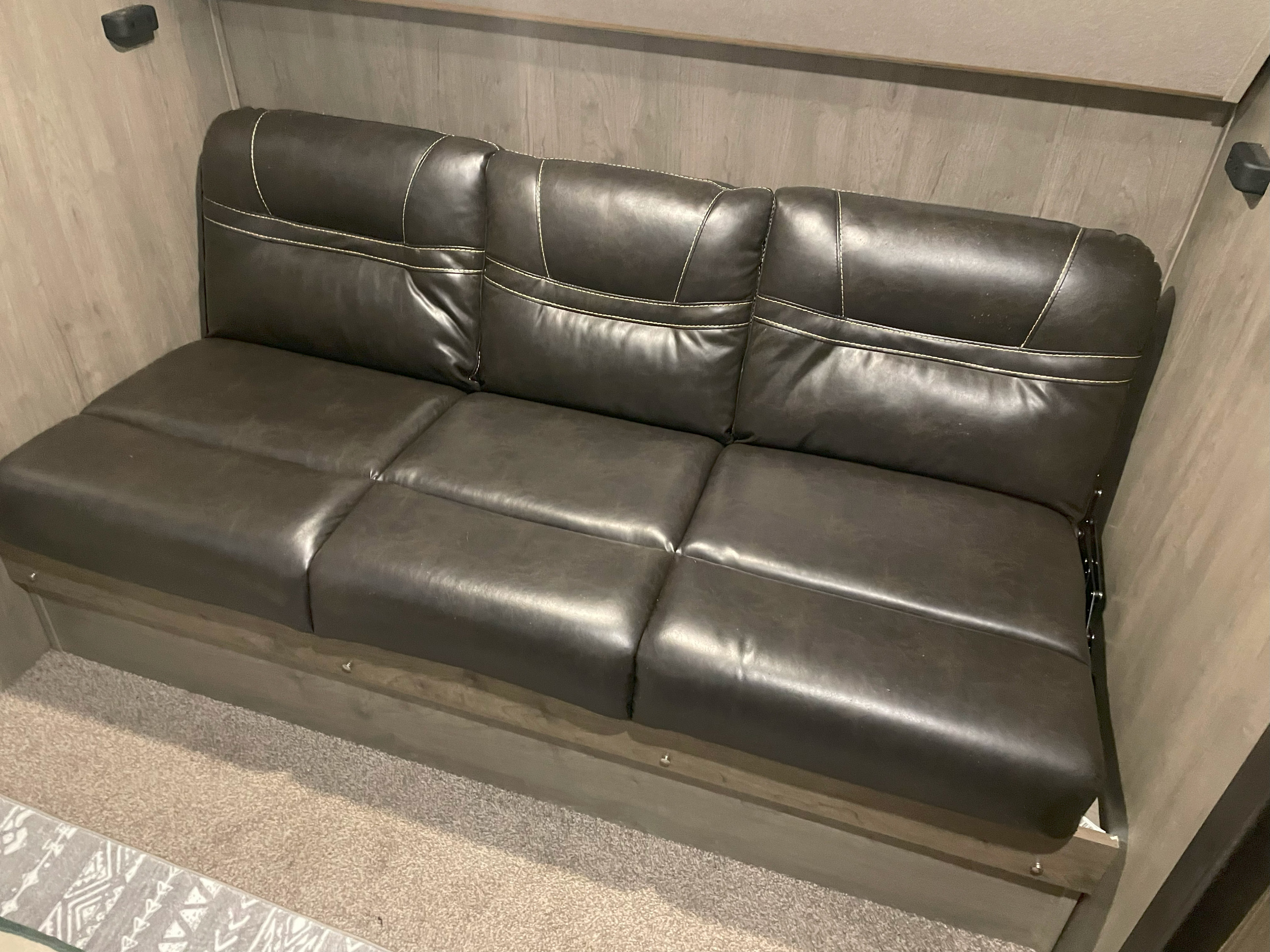 Cozy brown multi-section sofa in an RV rental, likely converts to a bed, offering versatile seating and sleeping.. Palomino Puma 32BHKS 2020