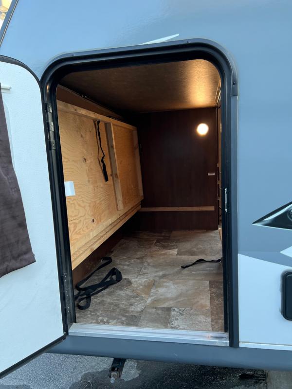 RV rental interior: Spacious compartment with wooden bed frame/storage, tiled floor, and warm ceiling light. Ideal RV touring.. Jayco Jay Feather 2016
