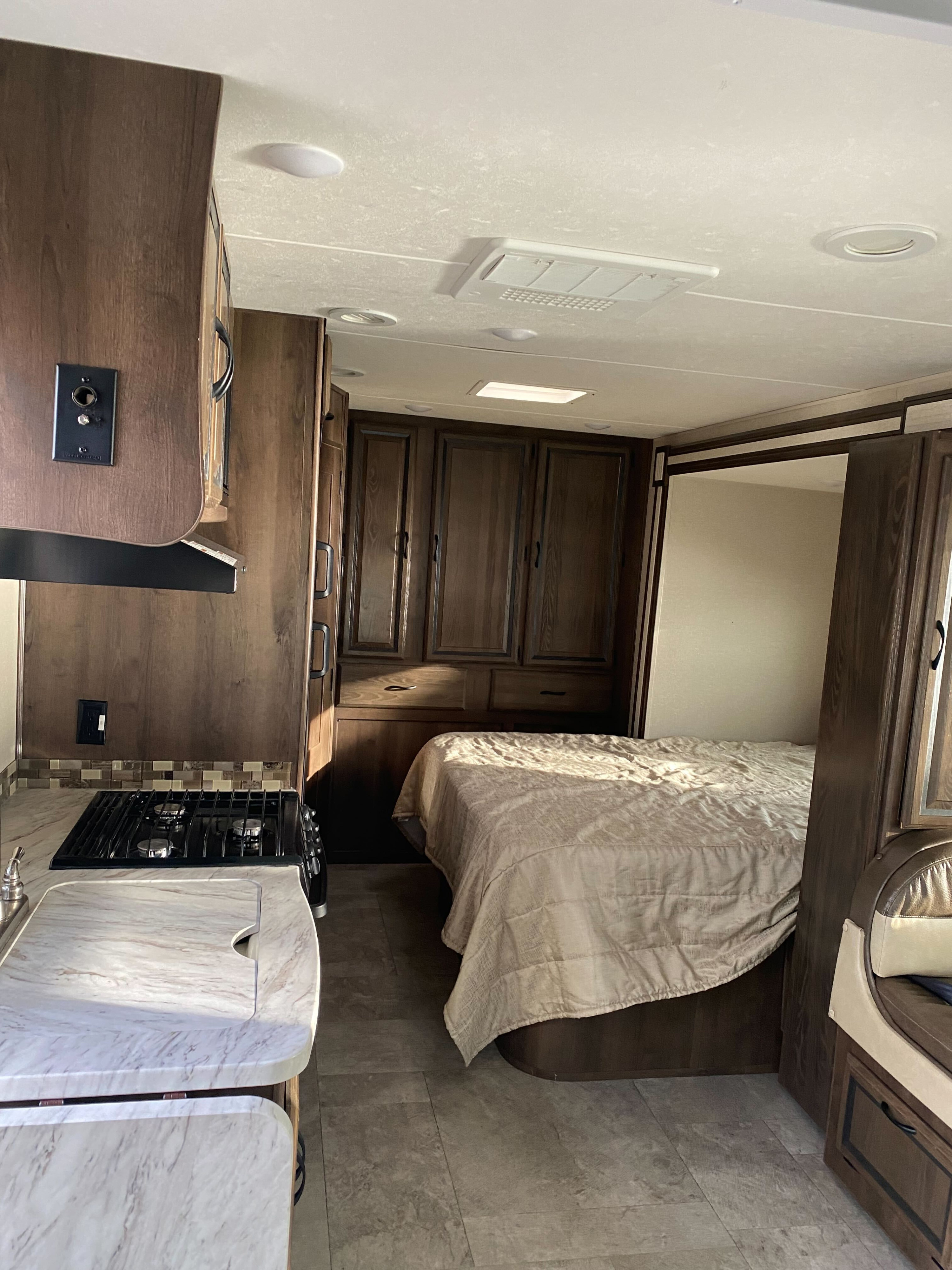 This rv rental features a well-equipped kitchen with stove & sink, flowing into a cozy bedroom with bed and wood cabinets.. Coachmen Mercedes Sprinter 2018