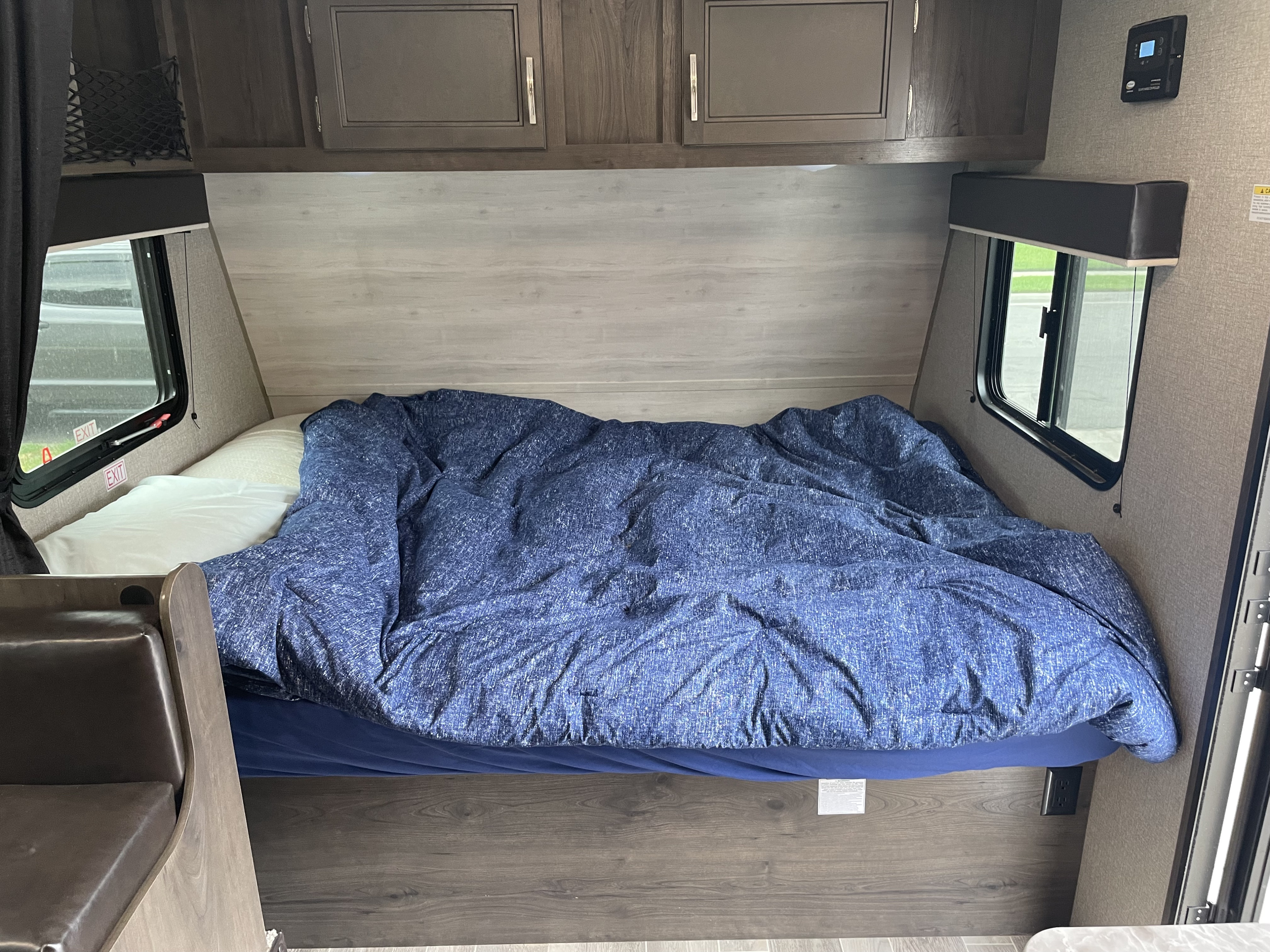 Cozy RV rental bedroom with a comfy bed, blue duvet, overhead cabinets, and dual windows for light.. Jayco Jay Flight 2021