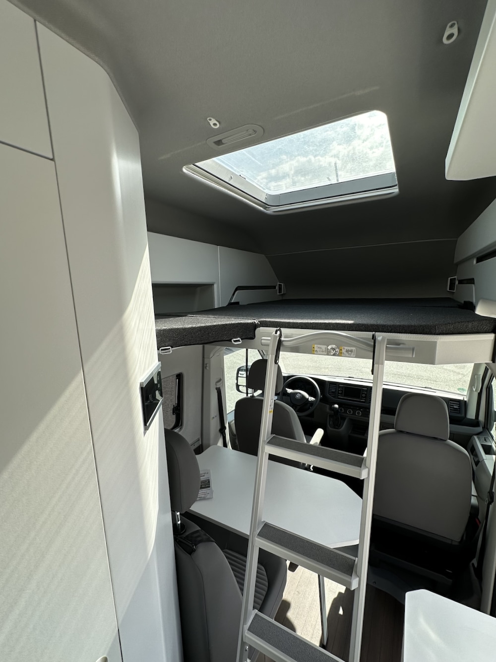 Modern RV rental interior: bunk bed with ladder, dining area, and skylight.. Volkswagen California 2022