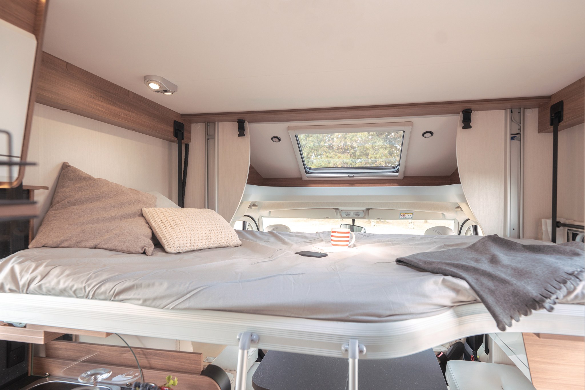 Cozy overhead sleeping area in an RV rental, featuring a comfortable bed, pillows, and a skylight above.. PILOTE P 726 FGJ 2024