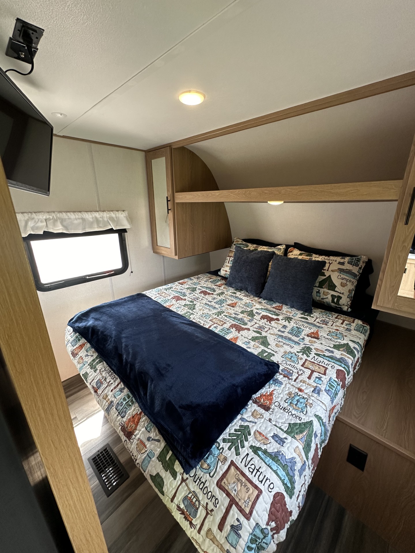Cozy RV rental bedroom with nature-themed bedding, compact design, and overhead storage. Perfect for camping adventures.. Forest River Prime TIME 2022