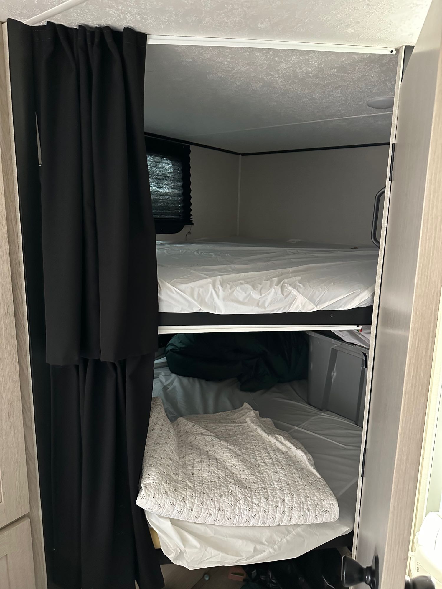 Cozy bunk beds with privacy curtain inside an RV rental, perfect for family adventures on the road.. Coachmen Apex 2021