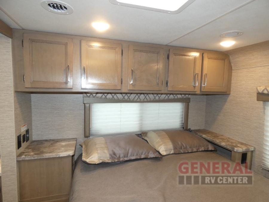 This RV rental bedroom features overhead cabinets, a window with blinds, and handy nightstands, offering compact comfort.. Thor Quantum SE 2022