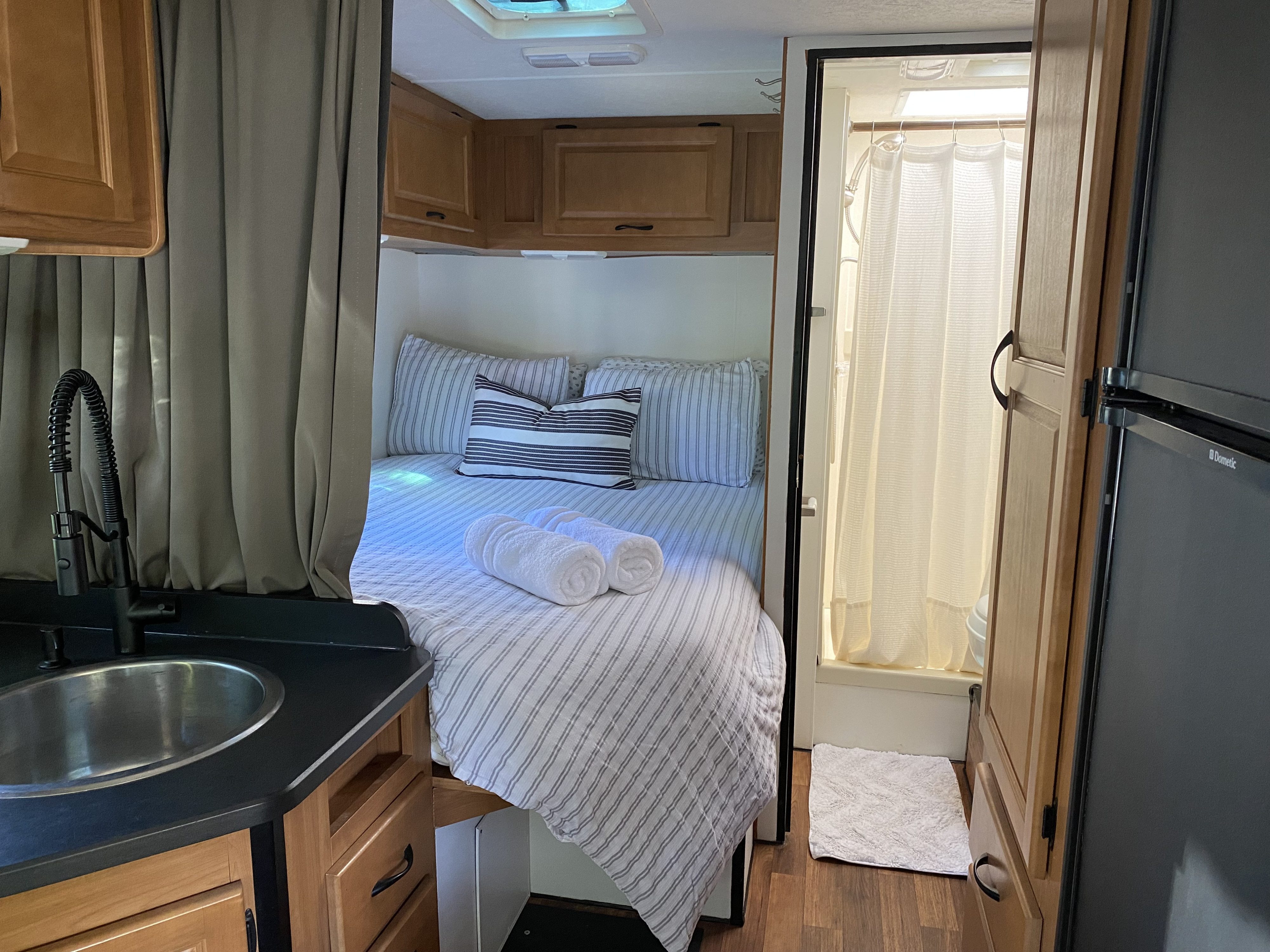 Well-appointed RV rental interior: includes a cozy bedroom with towels, compact kitchen with sink, and full shower. Ready for your trip!. Thor Majestic 2015