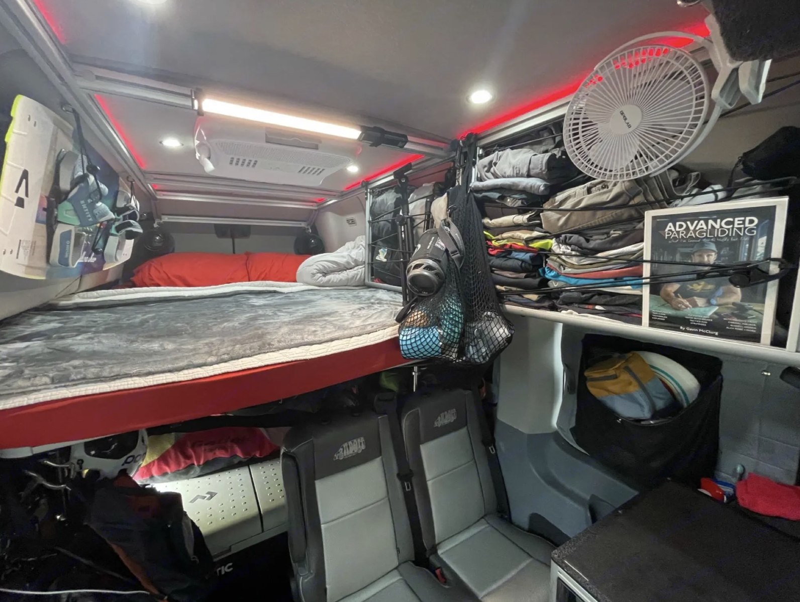 Functional RV rental interior with bunk bed, seating, and organized storage including gear for paragliding.. Ford Transit 2016