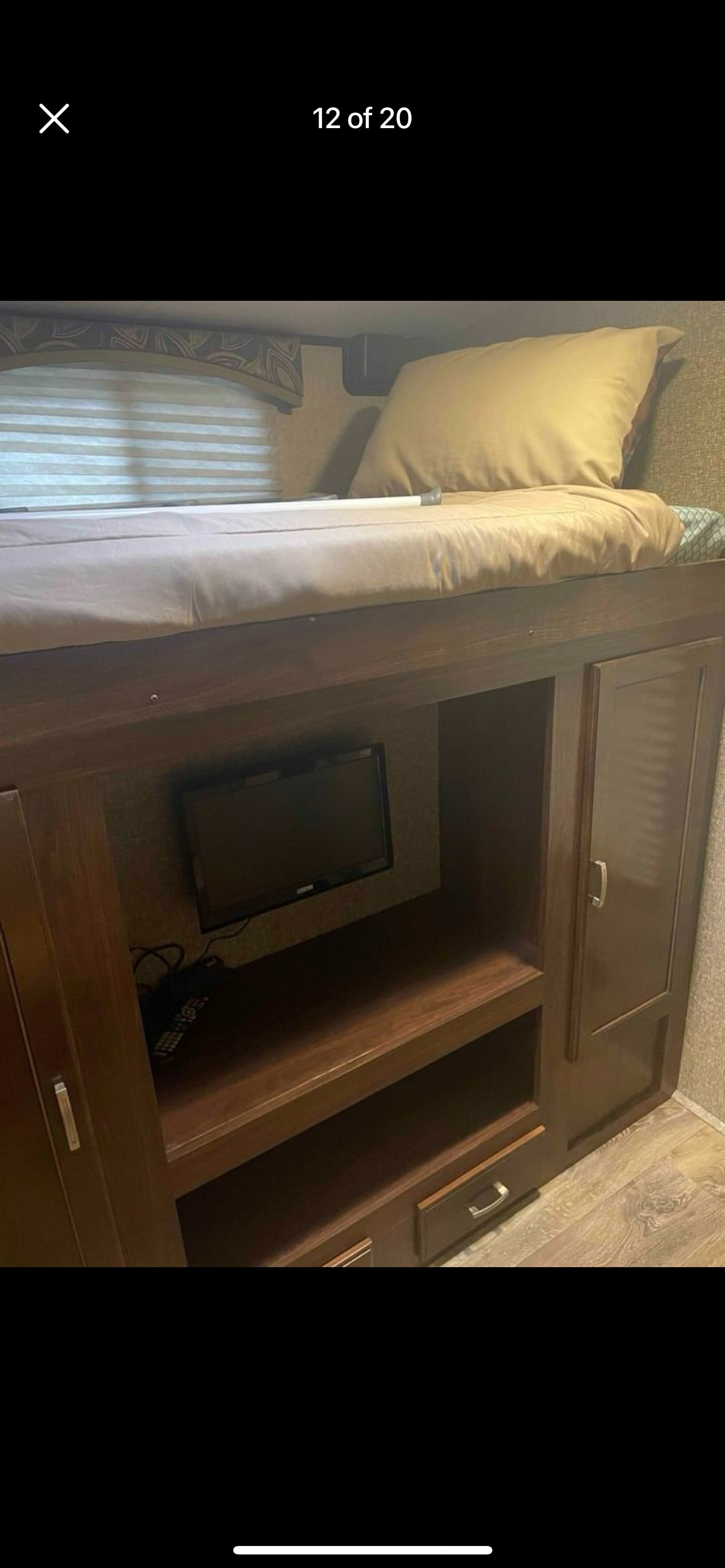 RV rental interior: a bunk bed over a built-in TV and storage unit with shelves and drawers.. Heartland RVs Sundance XLT 2016