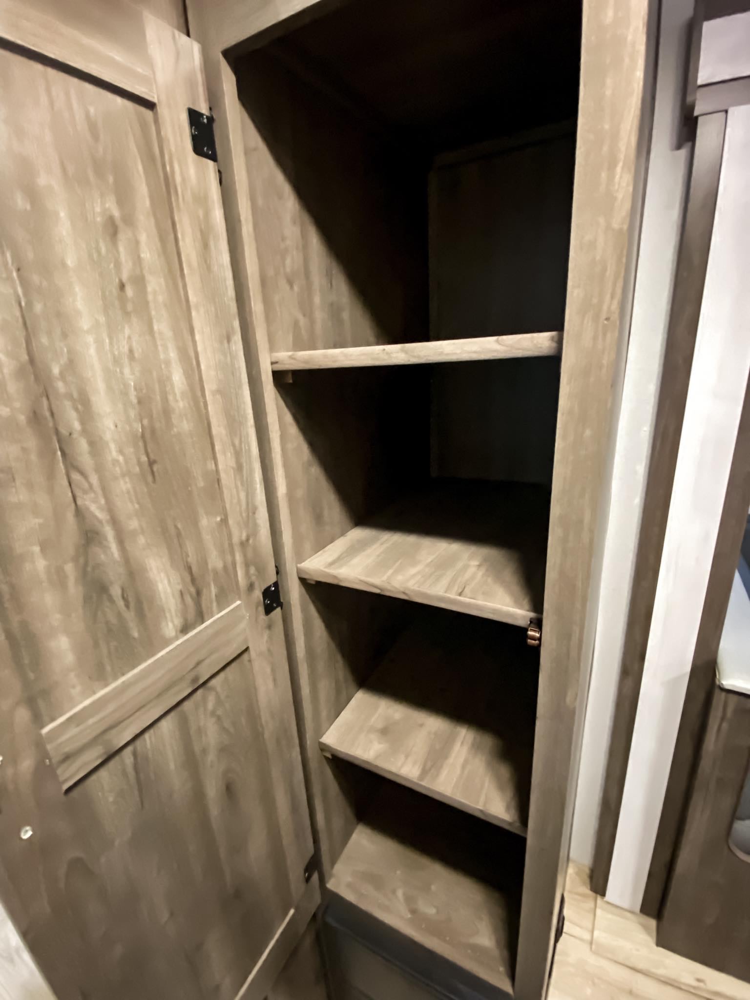 Interior view of this RV rental's open wood storage cabinet with multiple shelves, offering ample space.. Heartland RVs Pioneer 2024