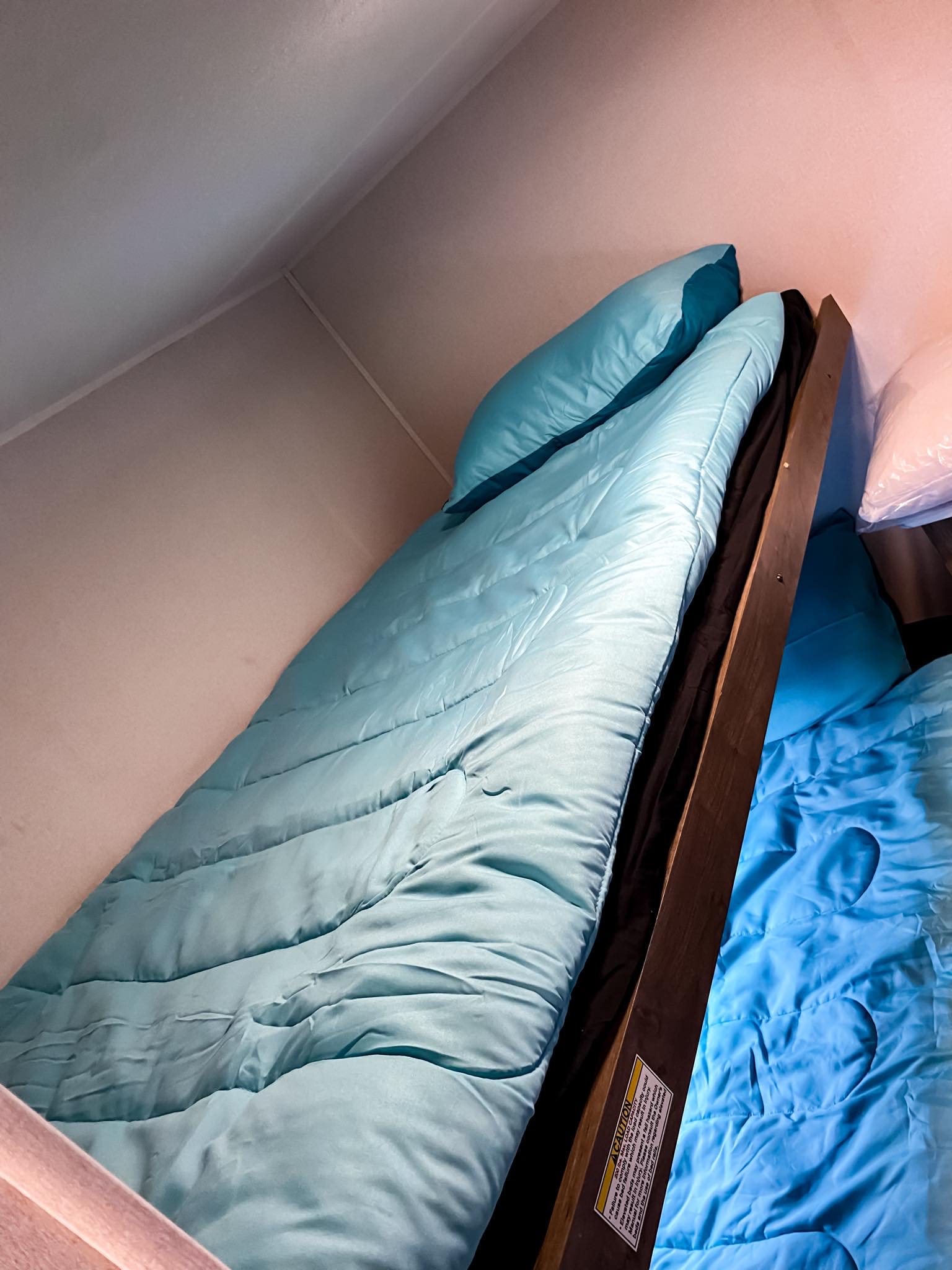 Cozy blue-bedded bunk beds inside an RV rental, providing compact and comfortable sleeping arrangements.. Heartland RVs Pioneer 2024