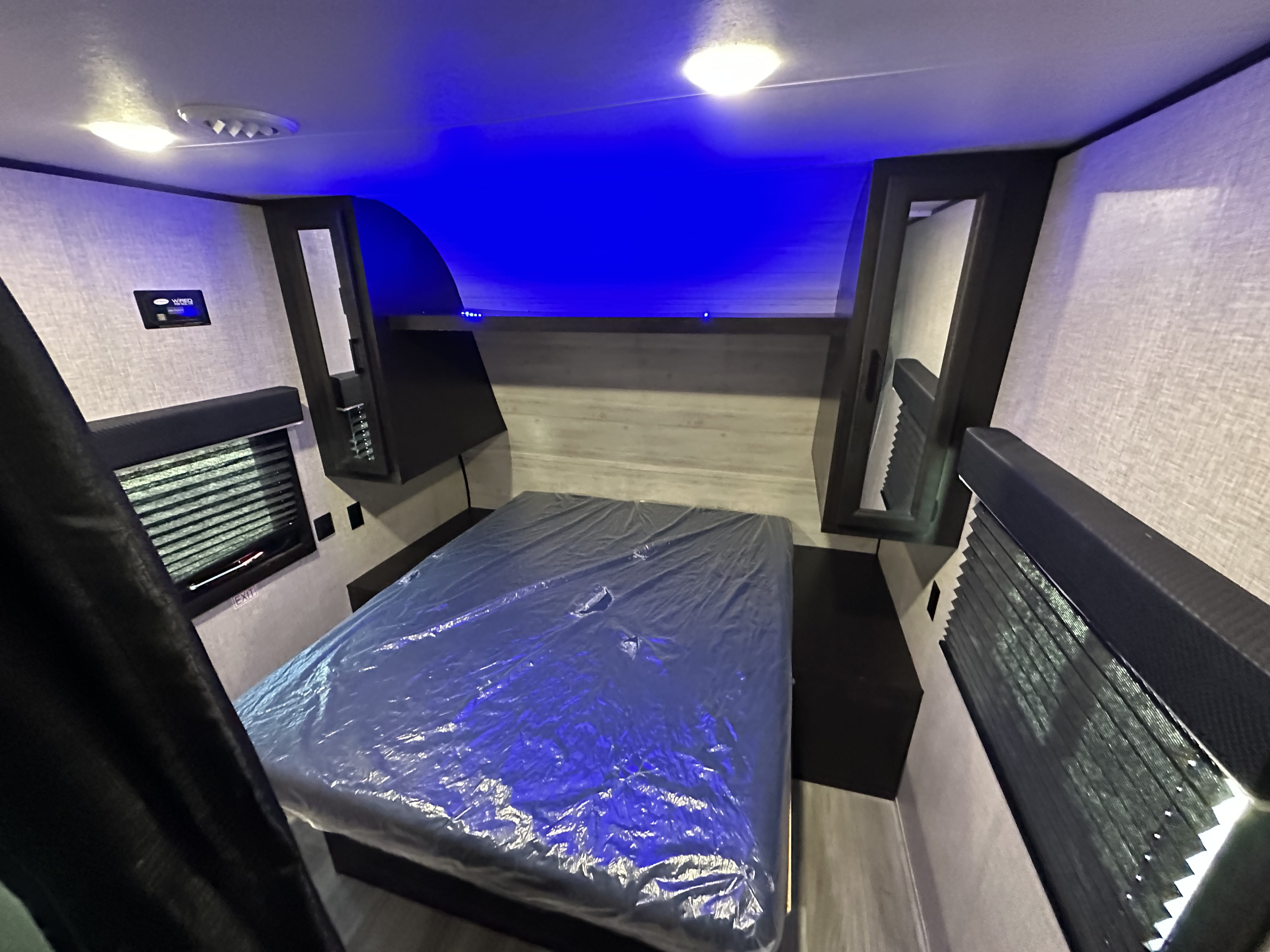 RV rental bedroom interior: new bed with bright and blue ambient lighting, wall-mounted controls, and windows.. Jayco 264BH 2022