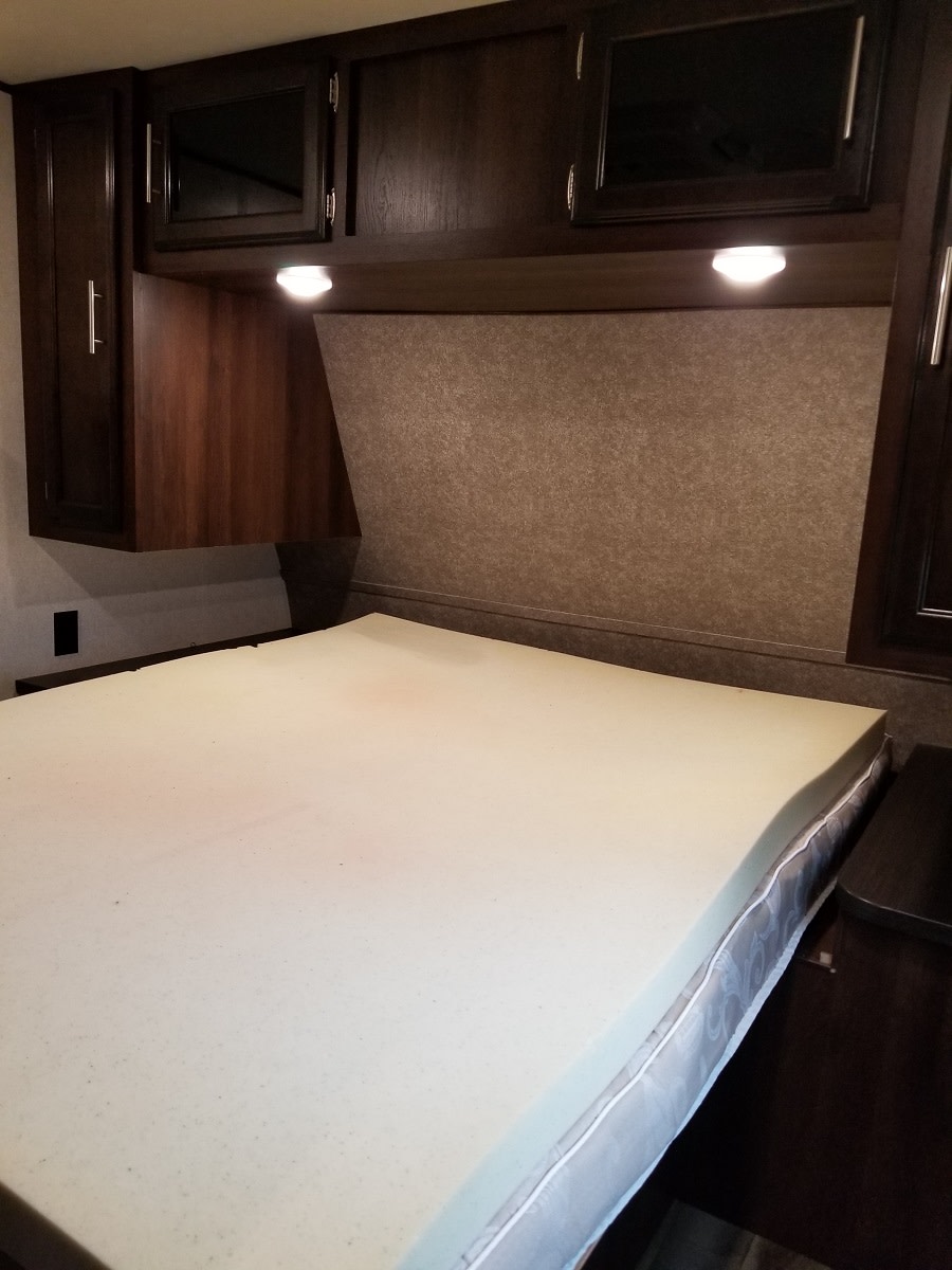 Inside an RV rental: A cozy bedroom with a bed, foam topper, dark wood cabinetry, and overhead reading lights.. Jayco Jay Flight 32BHDS 2019