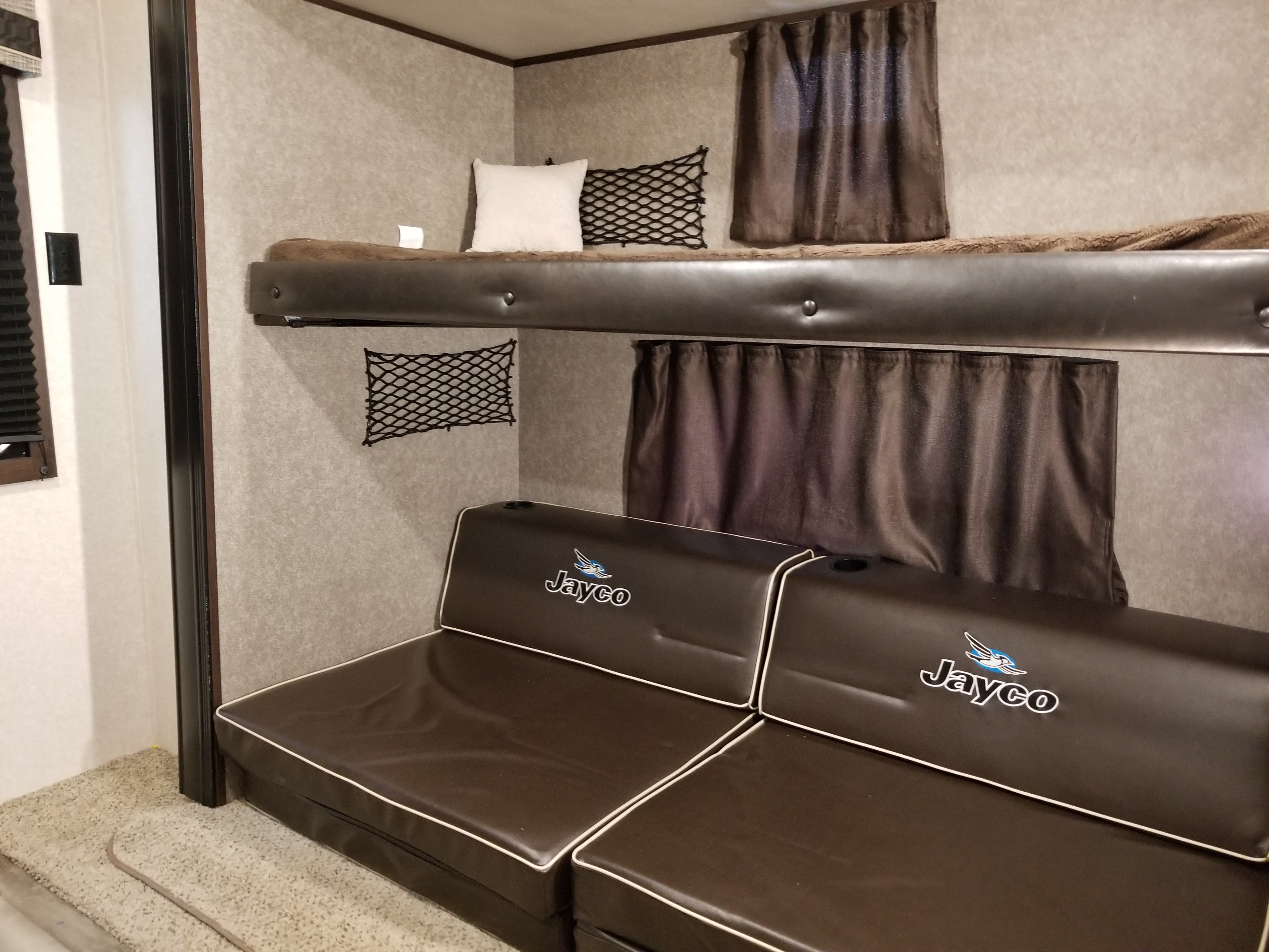 Spacious RV rental interior with comfortable bunk beds and a Jayco sofa. Includes privacy curtains & storage nets.. Jayco Jay Flight 32BHDS 2019
