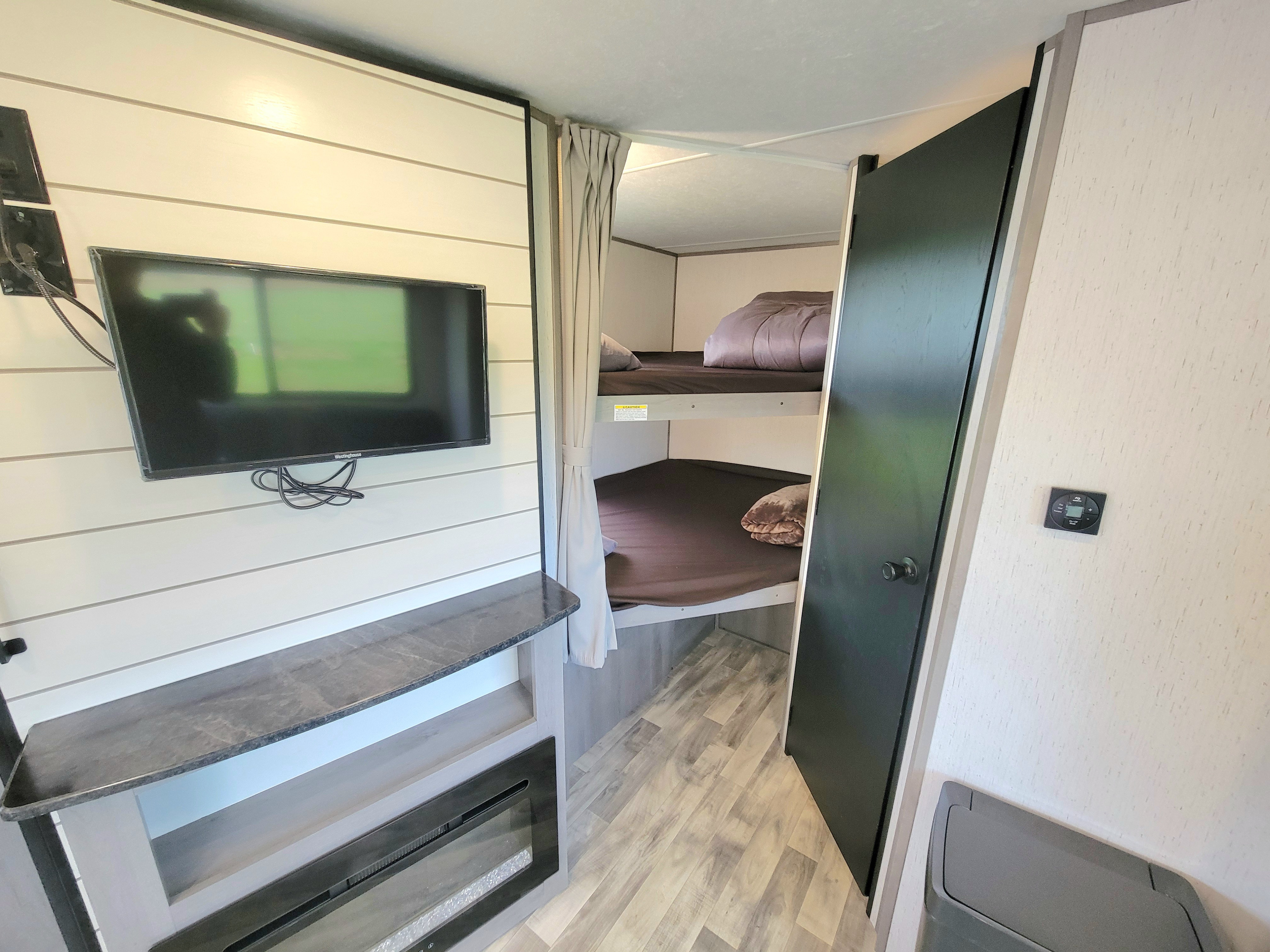This RV rental features cozy bunk beds, a TV, and a modern electric fireplace, offering comfortable amenities for your travels.. Dutchmen Kodiak 2022