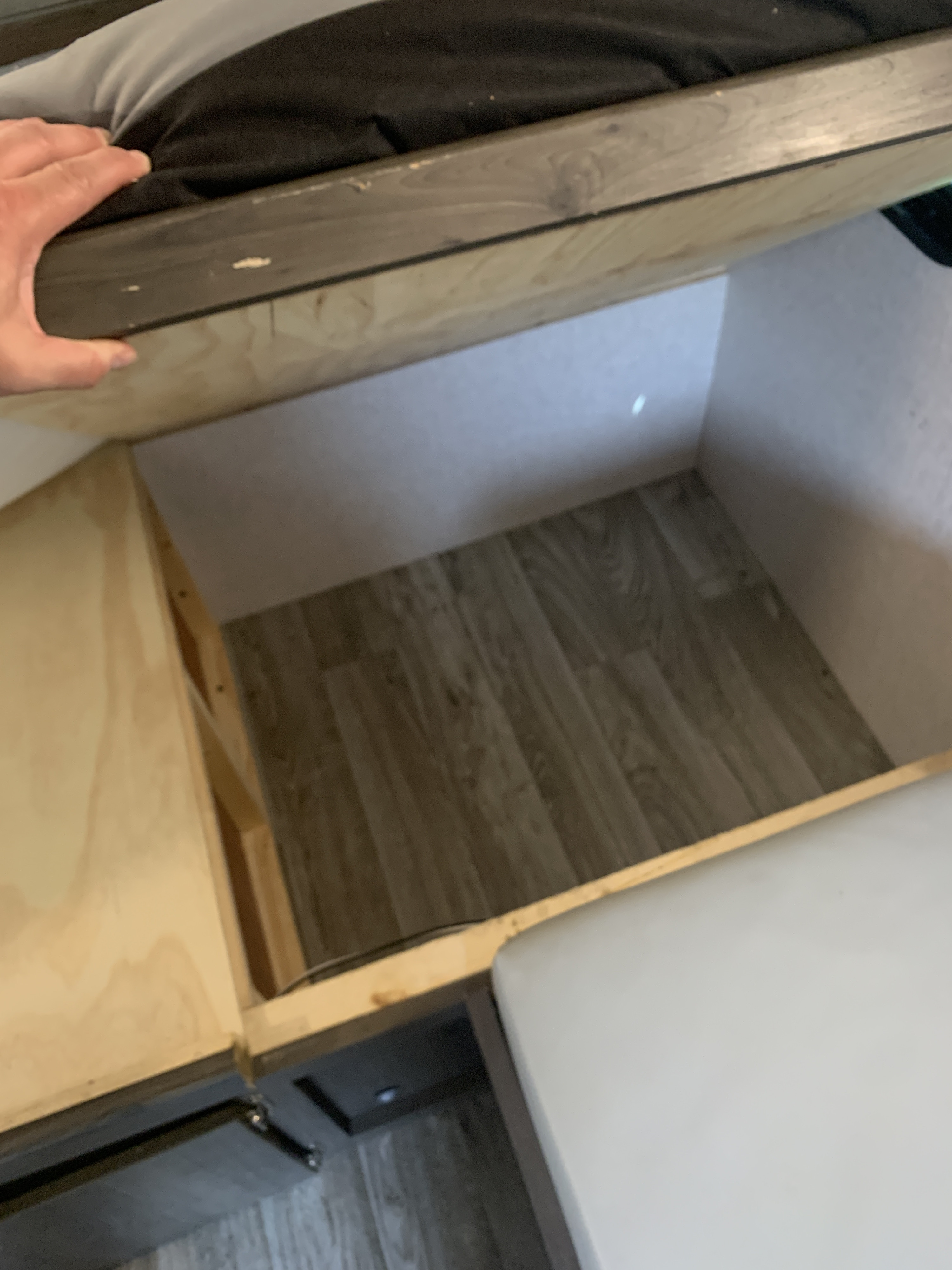 Peek into an RV rental's clever under-bed storage, showing light wood and laminate flooring.. Forest River Coachmen Express 2020