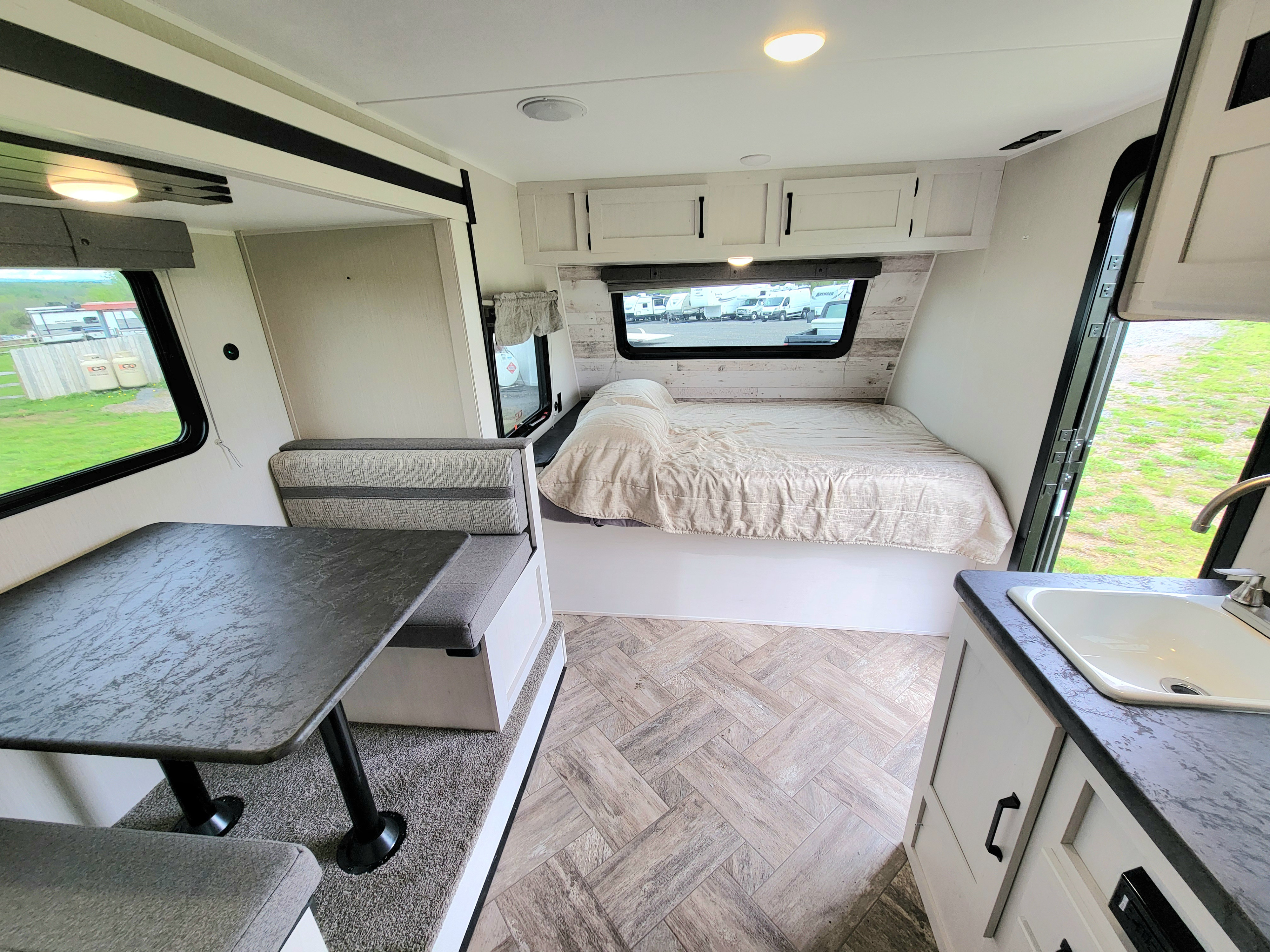 Bright RV rental interior. Features dining area, bed, and small kitchen with sink, offering comfort for your travels.. Palomino Puma 2023