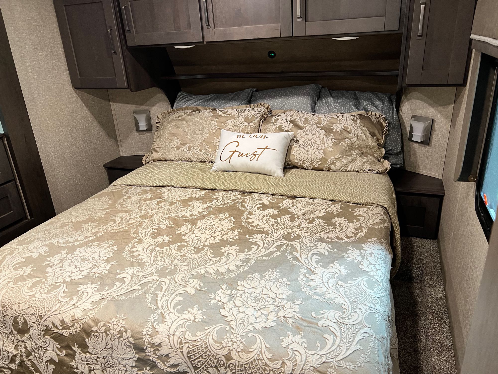 Experience comfort in this RV rental bedroom: A cozy bed with elegant patterned bedding, "Be Our Guest" pillow, and storage.. Grand Design Reflection RLS (Rear Living Area) 2022