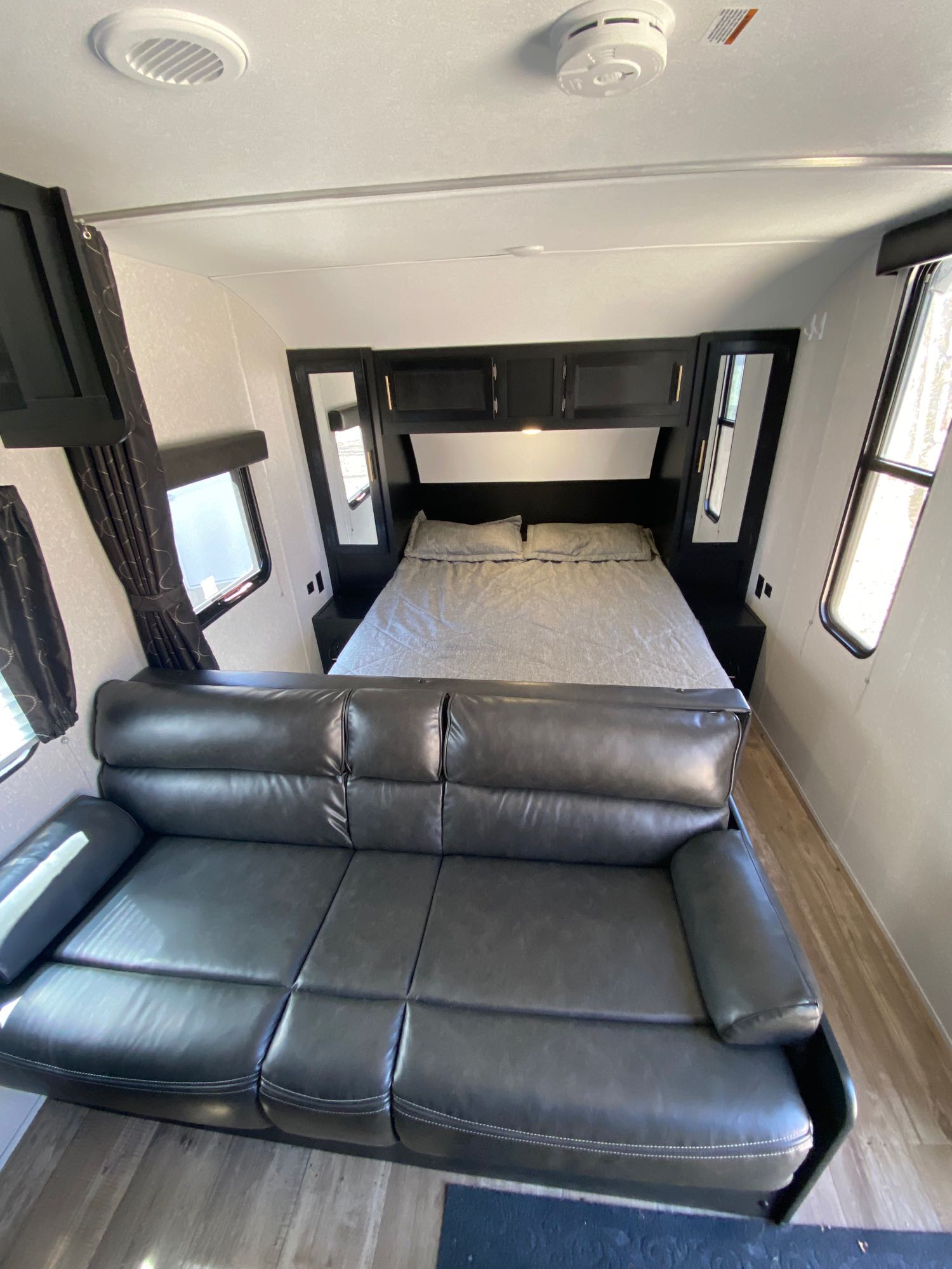 Experience comfort in this RV rental interior, featuring a neat bedroom with a bed and a large, dark leather sofa.. Forest River Cherokee Grey Wolf Special Edition 2022
