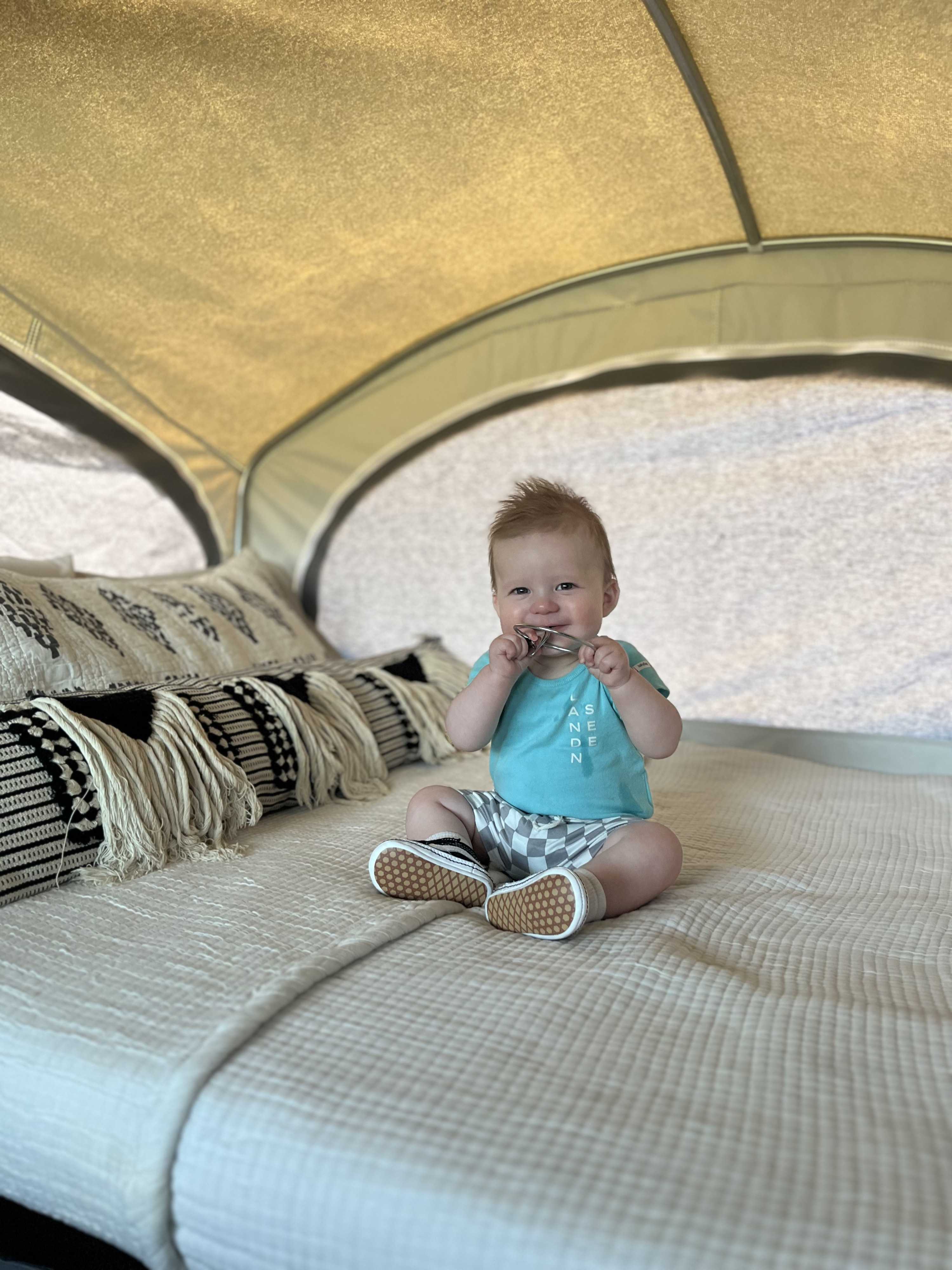 Adorable baby smiles from a cozy bed inside an RV rental, perfect for family camping and travel adventures.. InTech RV Flyer Explore 2022
