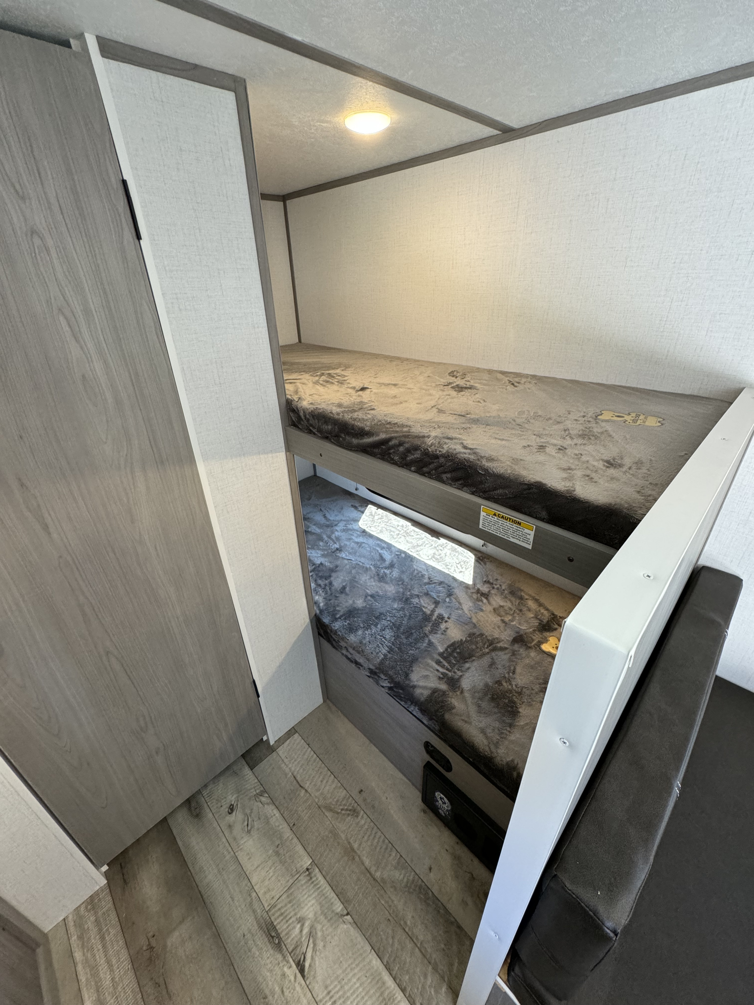 Inside an RV rental, featuring two stacked bunk beds with soft, dark grey blankets, perfect for family sleeping.. Keystone RV Coleman 17b 2024