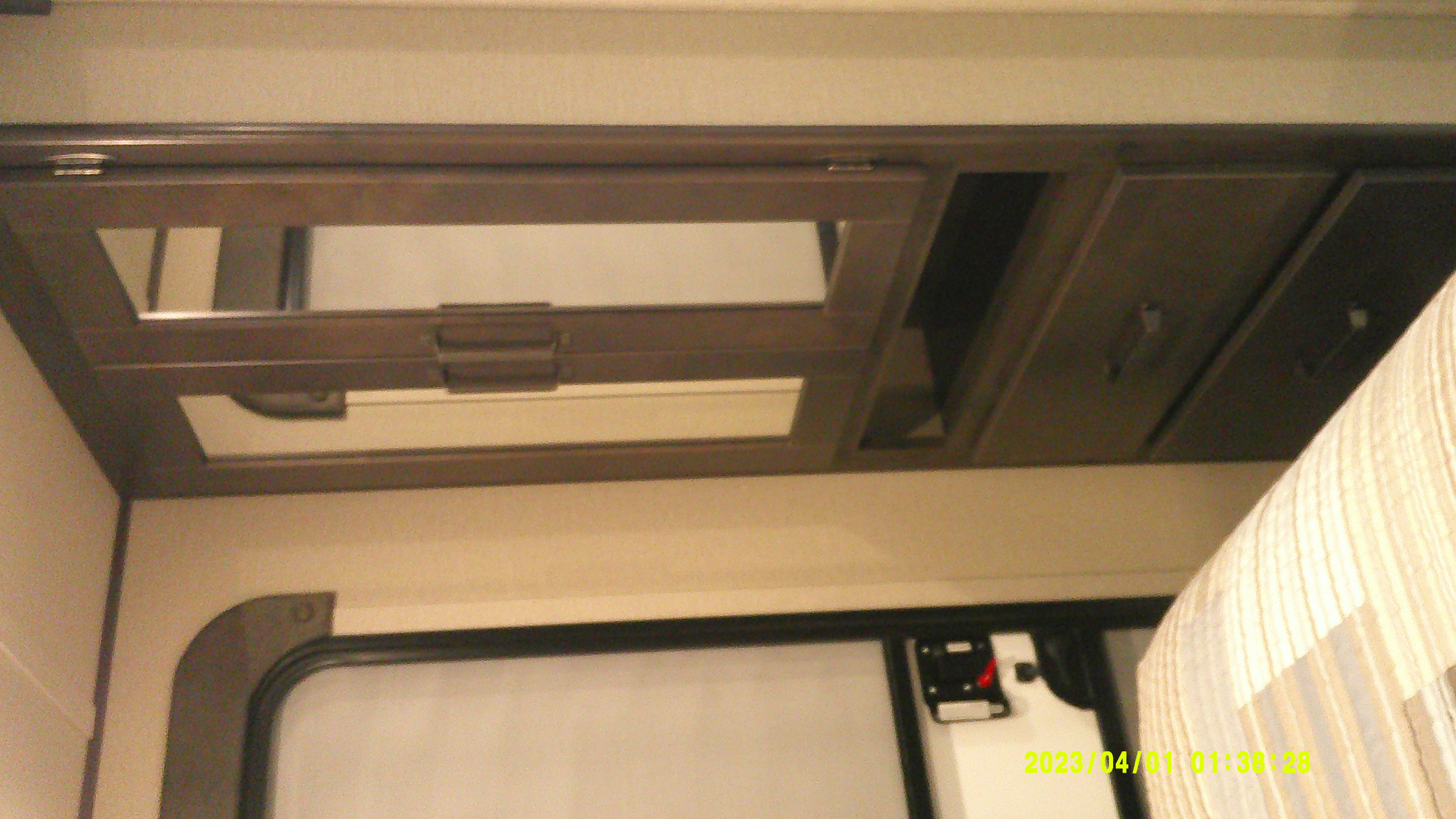 RV rental interior: open overhead cabinet, window, and striped curtain detail, offering a glimpse of the mobile living space.. Grand Design Explor 2022