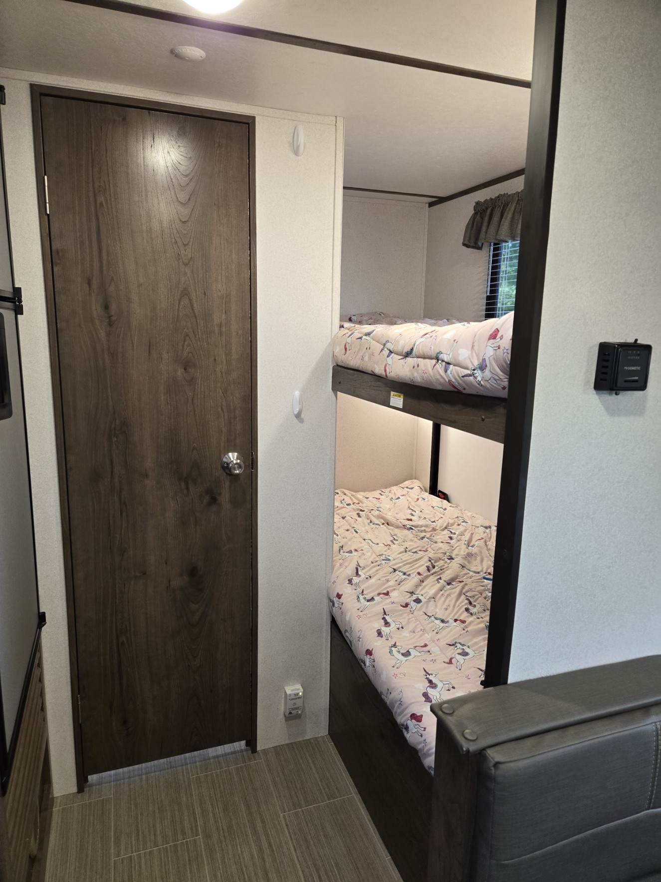 RV rental interior: cozy bunk beds with playful unicorn bedding and a sturdy wooden door.. Keystone RV Passport SL 2021