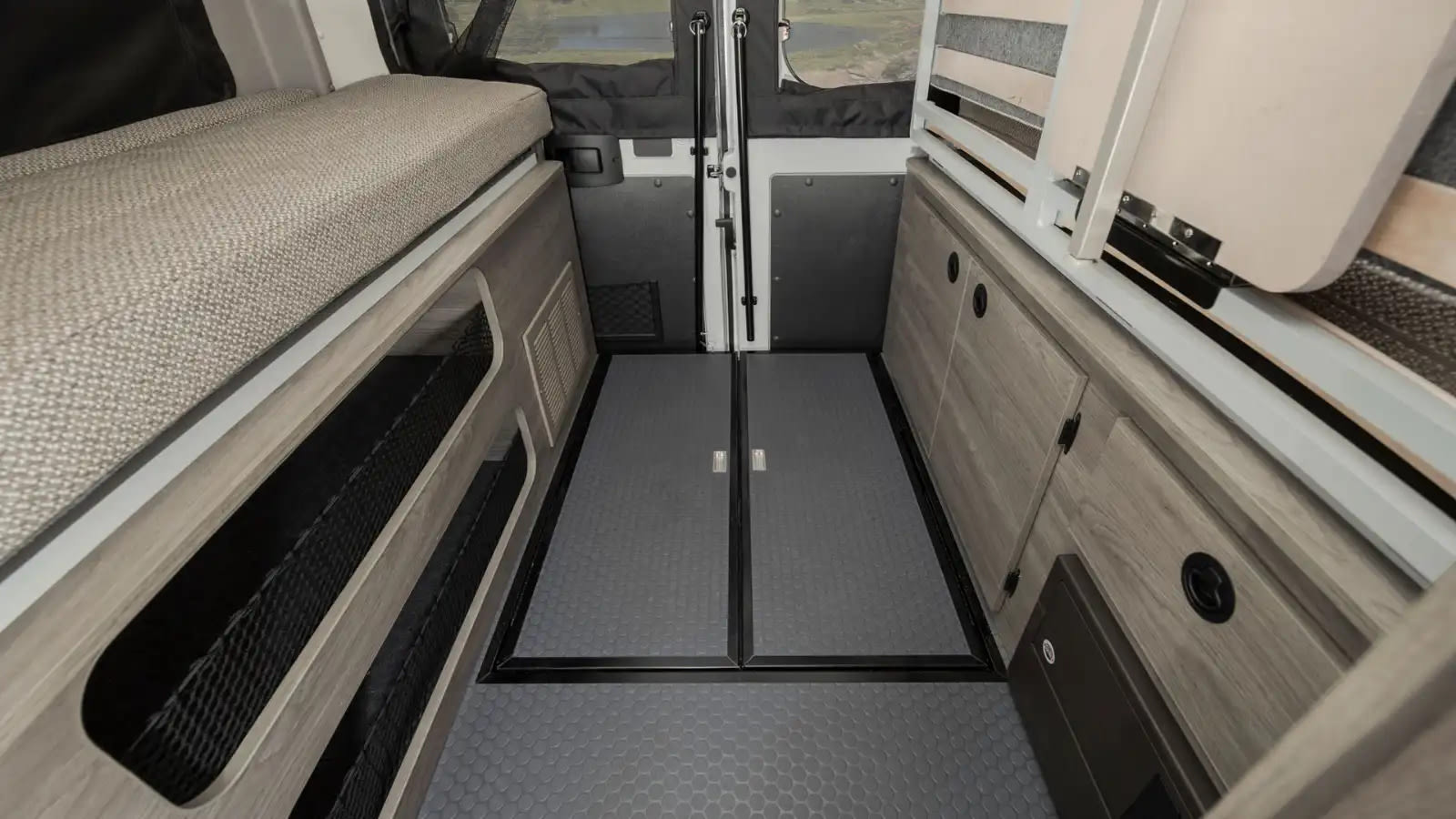 This RV rental's camper van interior showcases a cozy sleeping area, ample storage, and rear doors, ideal for road trips.. Winnebago Solis 2023