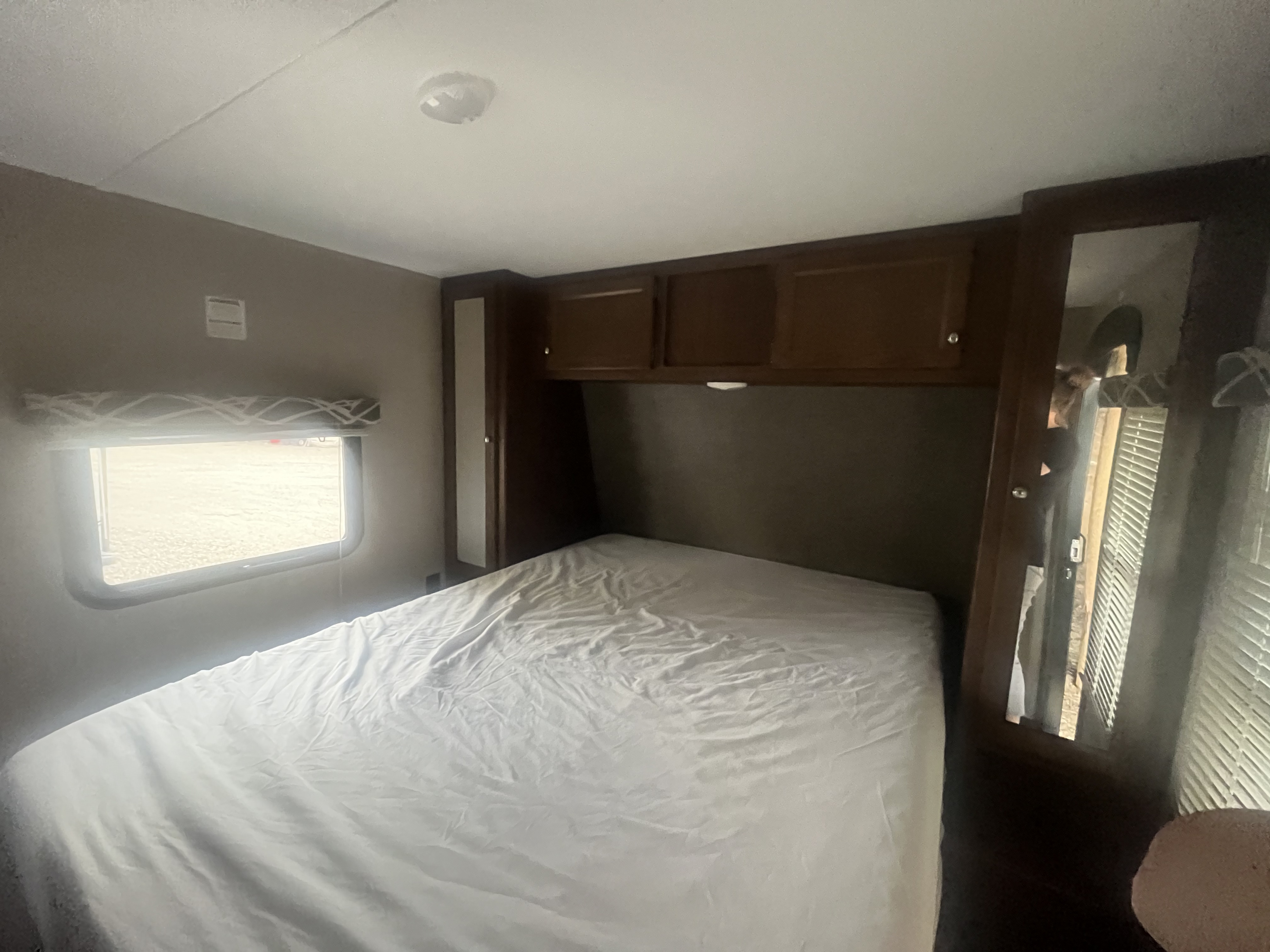 Cozy RV rental bedroom featuring a comfortable bed, overhead cabinets, and a window for a relaxing stay.. Keystone RV Hideout Luxury 2017