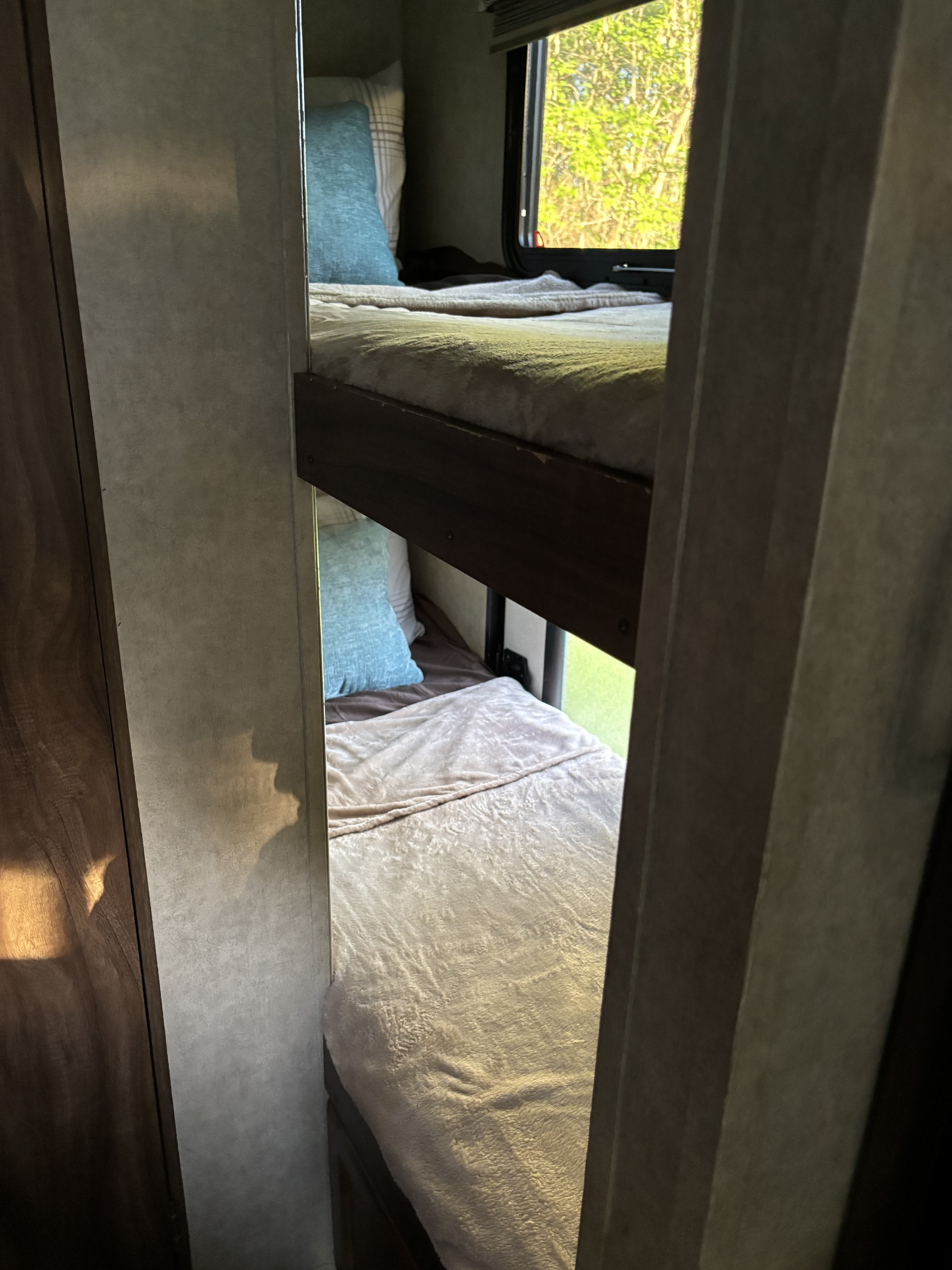 Comfy bunk beds inside an RV rental with a bright window view.. Coachmen Clipper 2017
