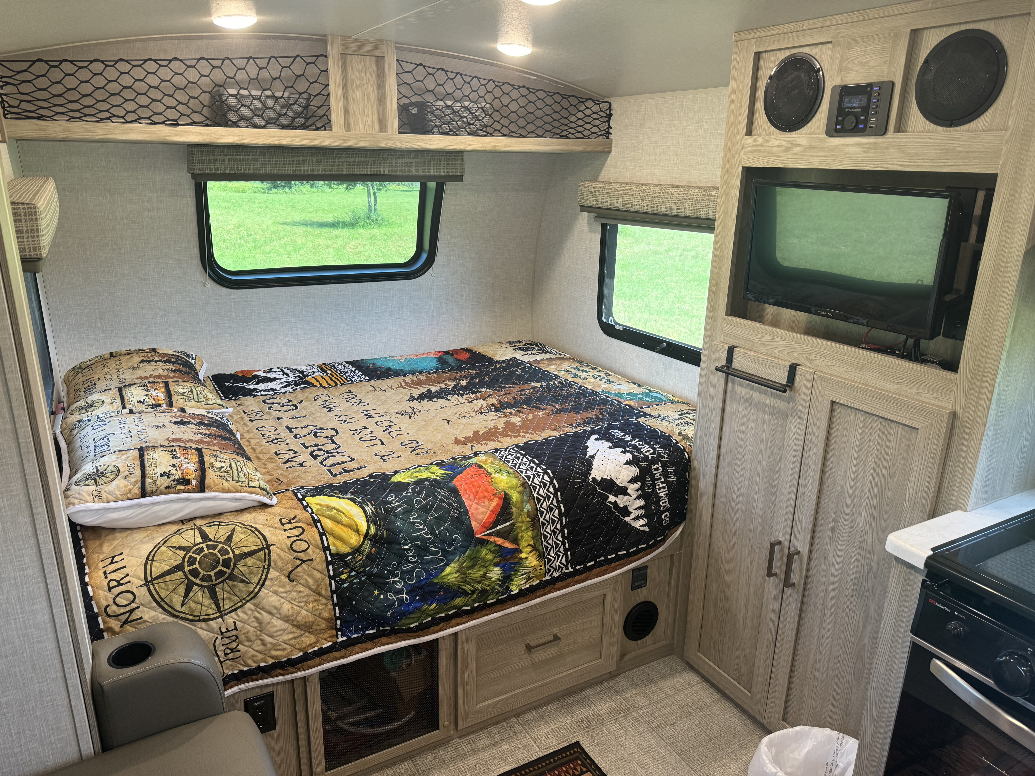 Cozy RV rental interior featuring a themed bed, TV, compact kitchen, and overhead storage for comfortable travel.. Forest River Flagstaff E-Pro 2020