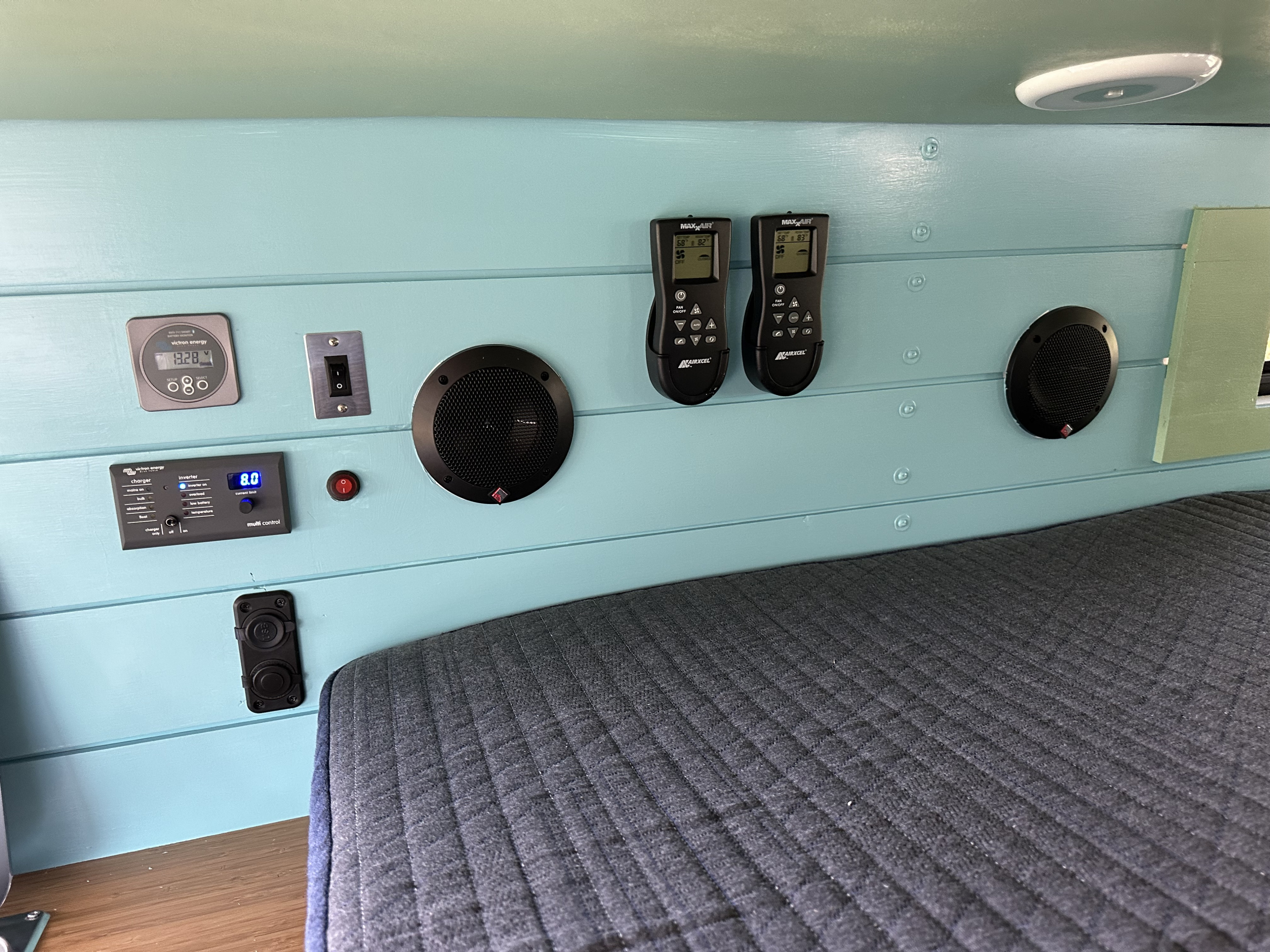 RV rental interior: Victron Energy power, Maxx Air climate, and audio controls on a blue wall above a bed. Optimized for comfort.. Mercedes-Benz Sprinter 2021