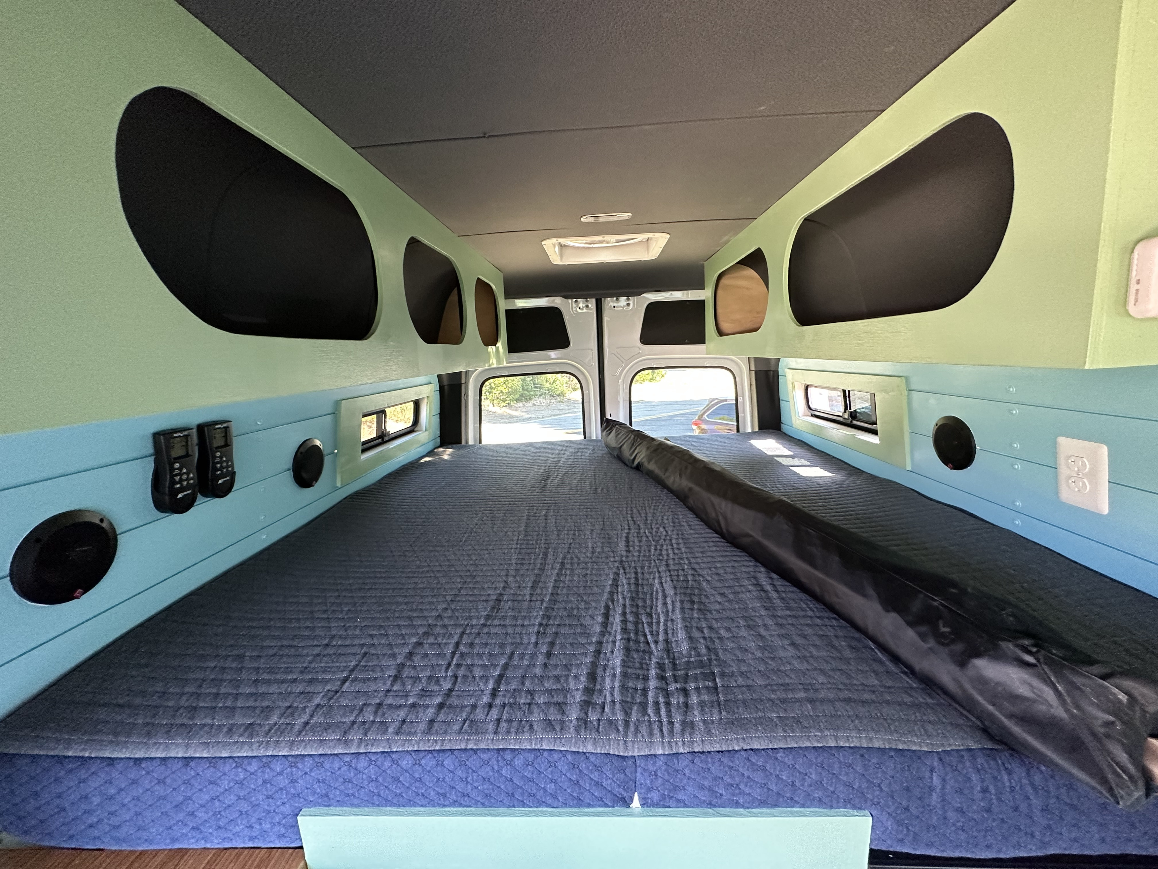 Inside a modern RV rental: view of custom interior with twin beds, built-in storage, and unique color scheme.. Mercedes-Benz Sprinter 2021