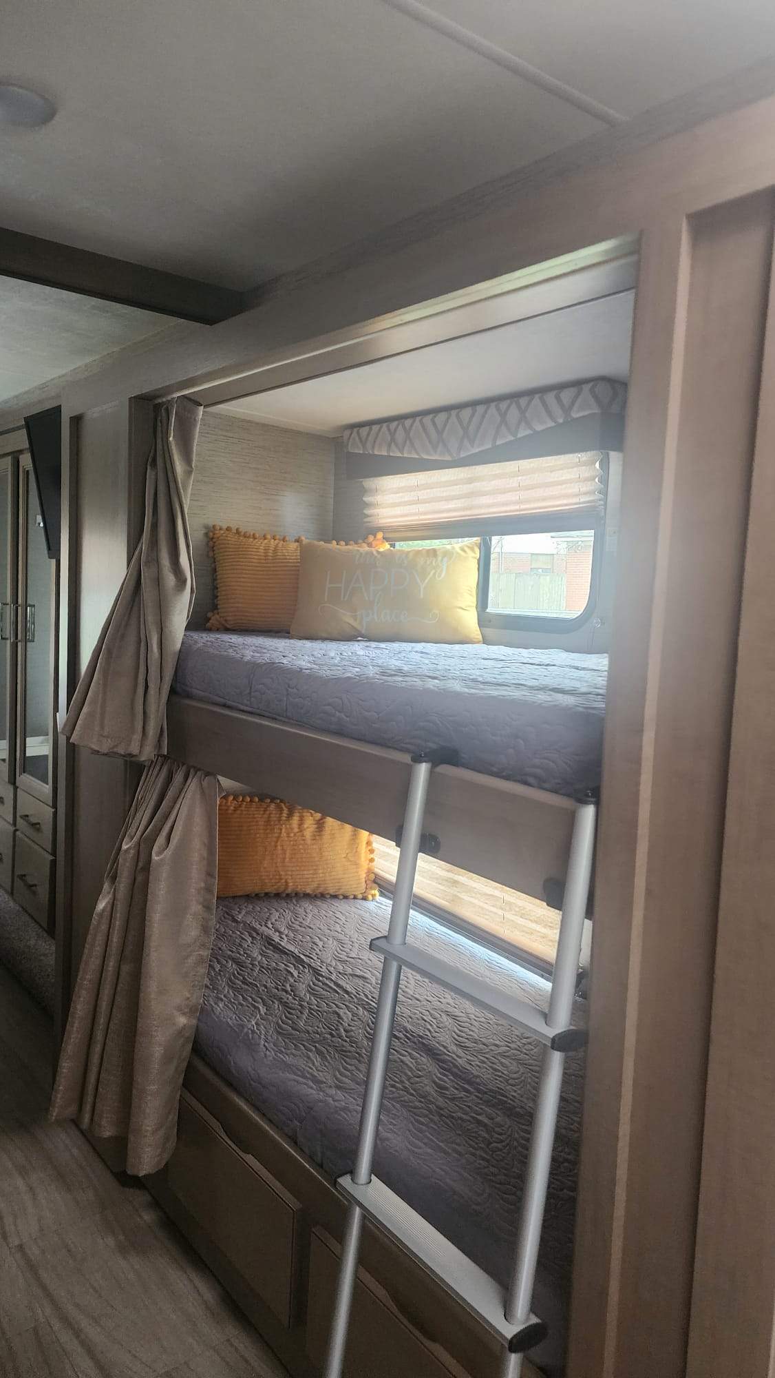 This RV rental features comfy bunk beds with yellow pillows, a ladder, and window blinds, offering a cozy sleeping space.. Thor Quantum 2021