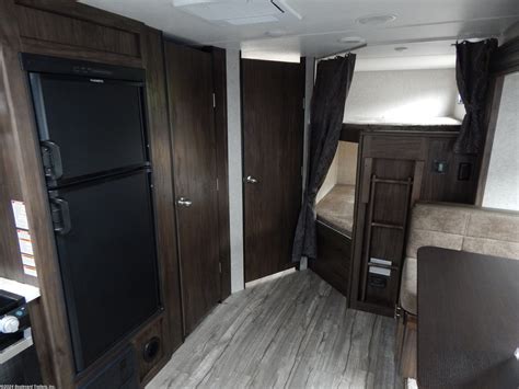 This RV rental offers a well-equipped interior: black refrigerator, bunk beds with curtains, and a dining area for comfortable travel.. Forest River Cherokee Grey Wolf 2021