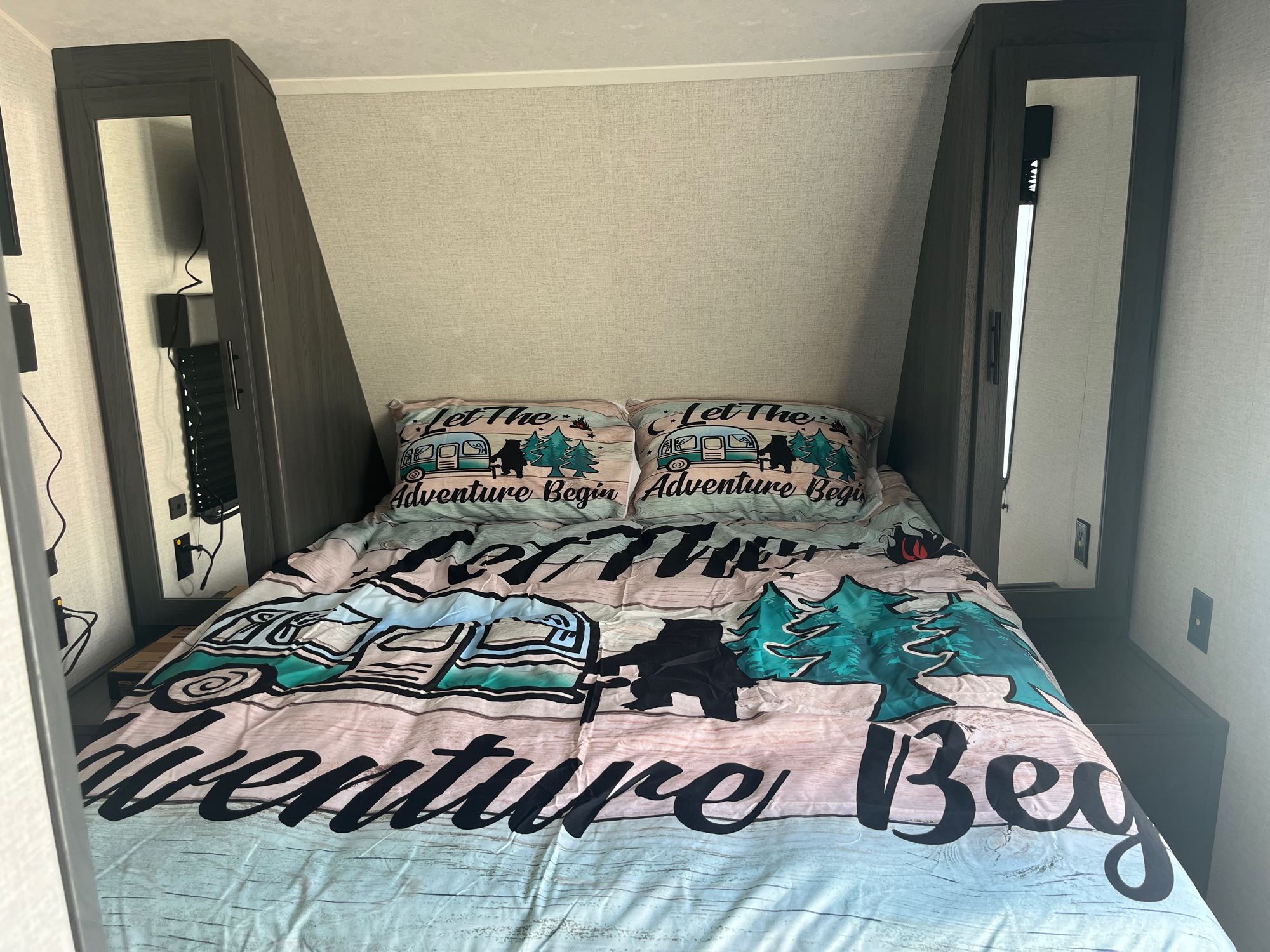 Cozy RV rental bedroom featuring "Let The Adventure Begin" bedding and built-in mirrored storage.. Dutchmen ASPEN TRAIL RD 2022