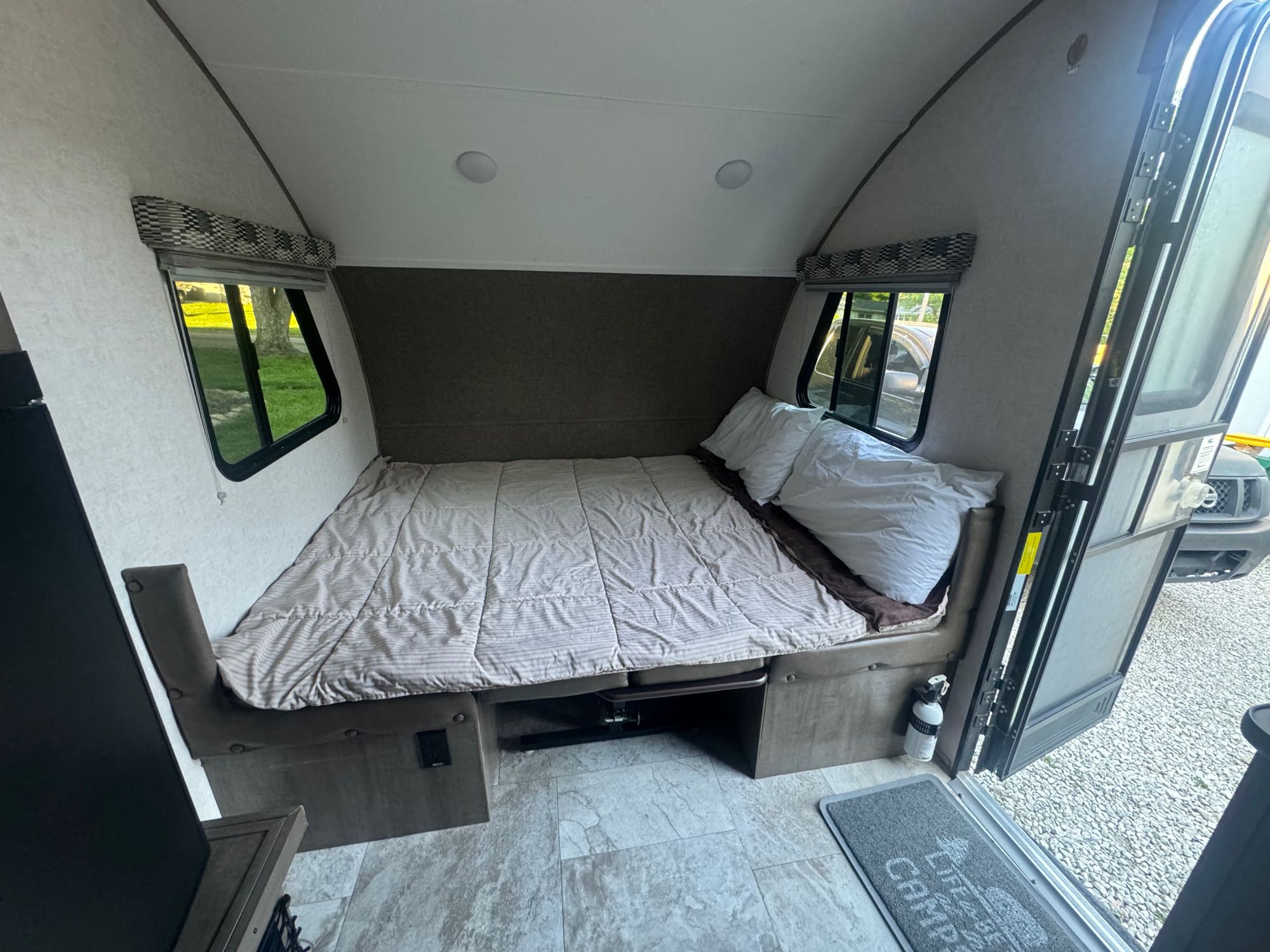 RV rental: The cozy sleeping area features a made bed with striped comforter, side windows, and an open entry door.. R-Pod R-Pod Trailer 2018