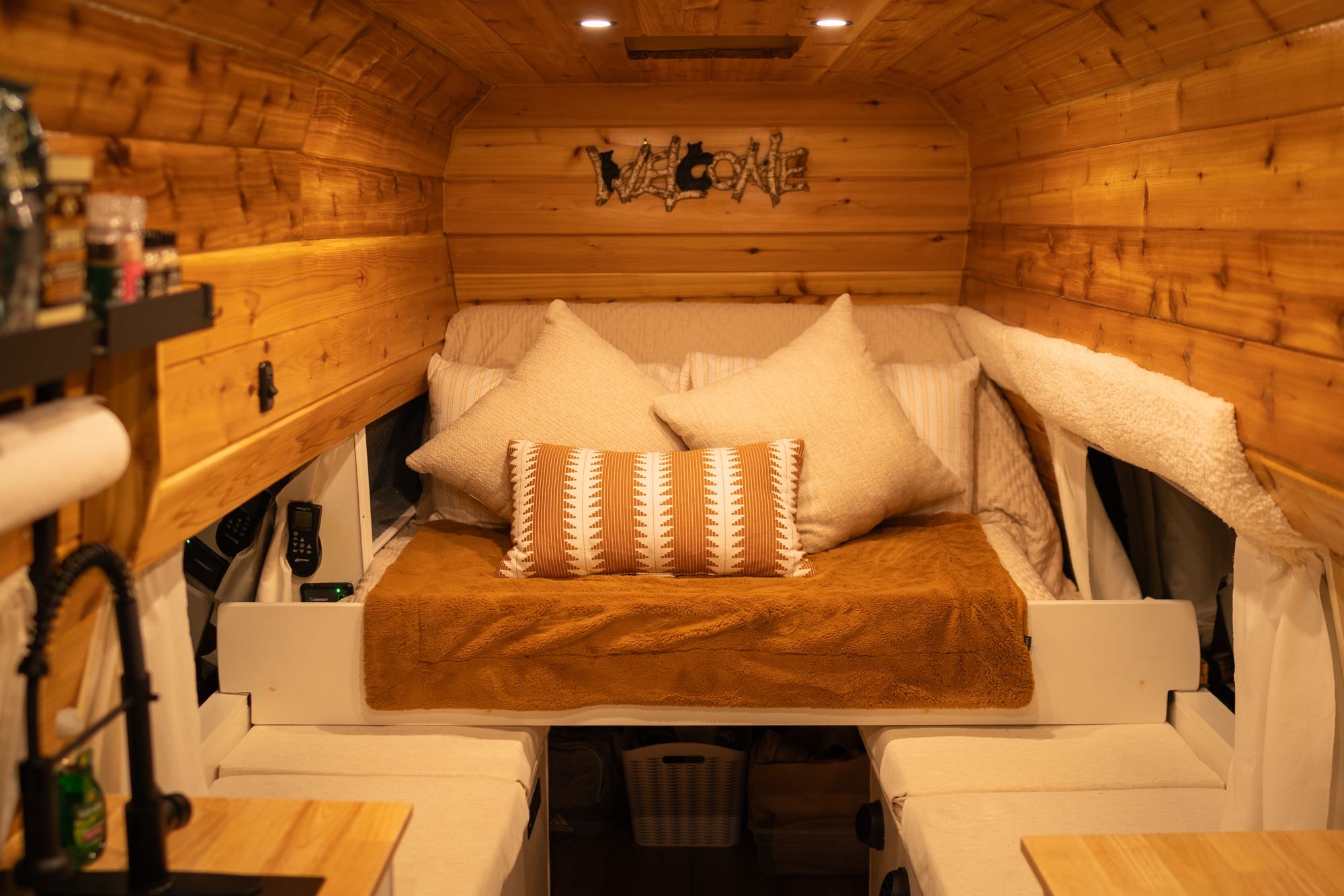 Cozy RV rental interior: wood-paneled walls, a comfortable bed with pillows, and a compact kitchen area for travelers.. Ford Econoline 2011