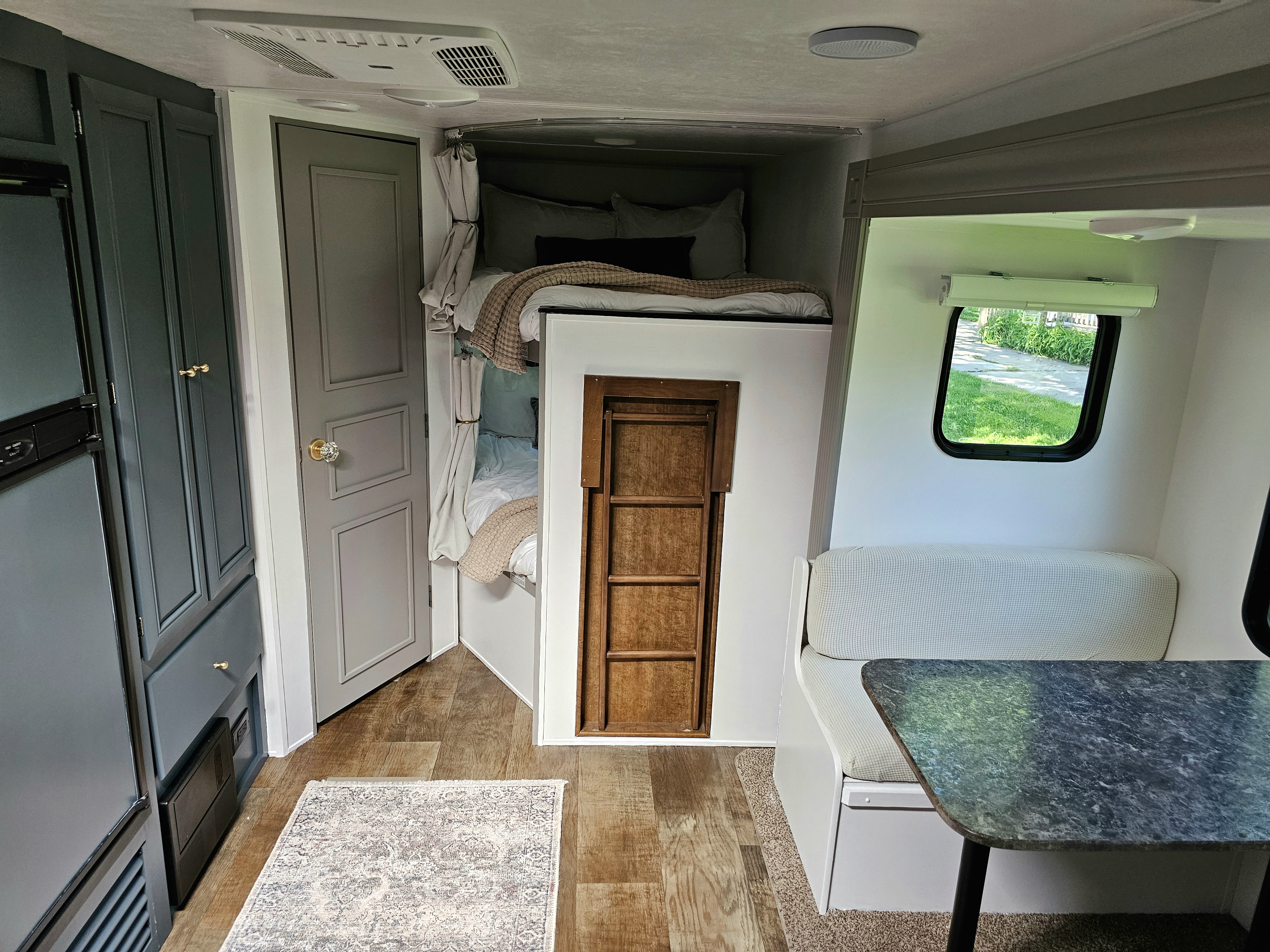 Explore this cozy RV rental interior featuring modern gray cabinetry, comfy bunk beds, a dinette, and a window view.. Crossroads RV Z-1 2017