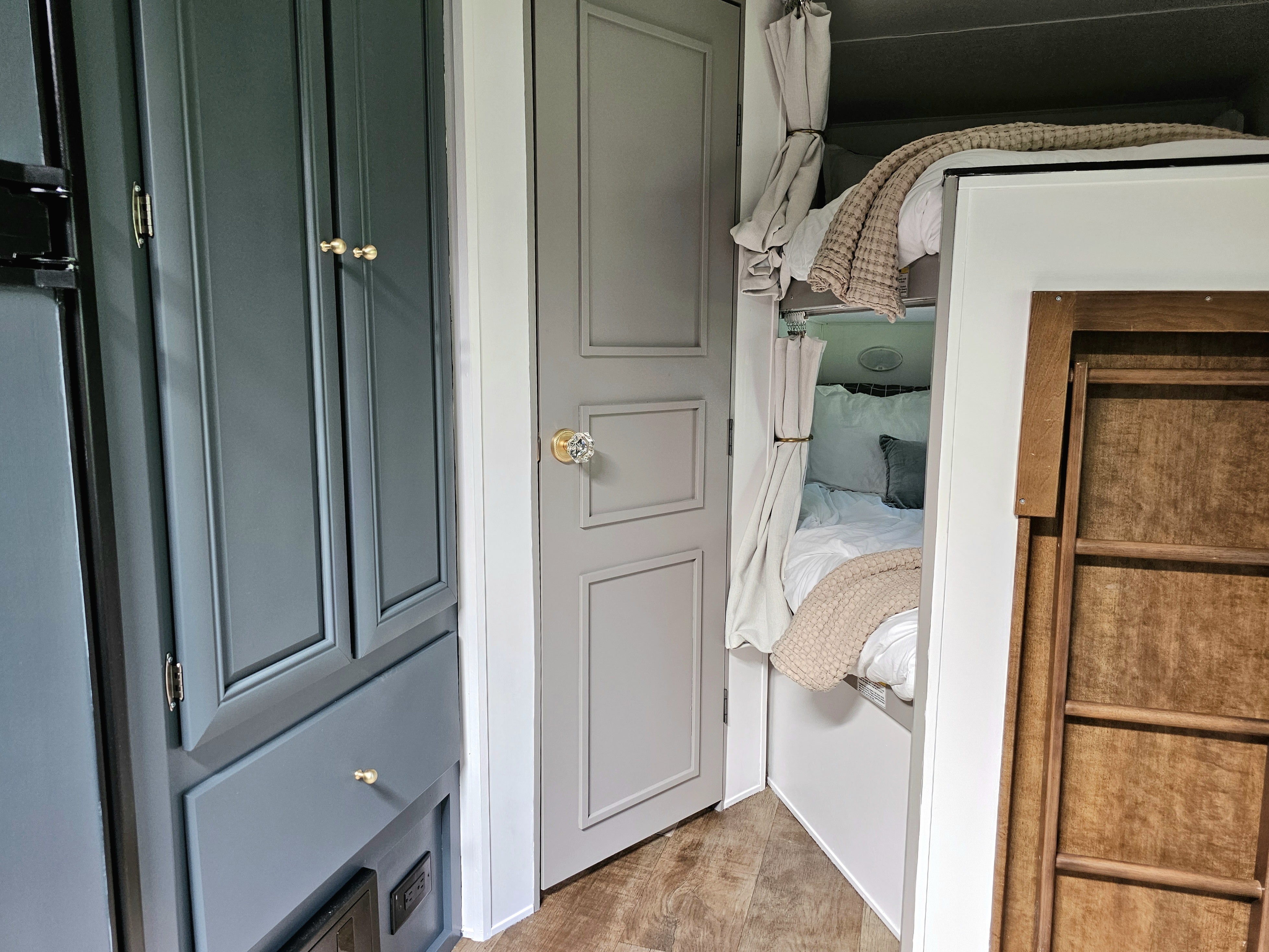 Cozy RV rental interior featuring stylish dark cabinets with gold knobs, a light gray door, and comfortable bunk beds with a ladder.. Crossroads RV Z-1 2017