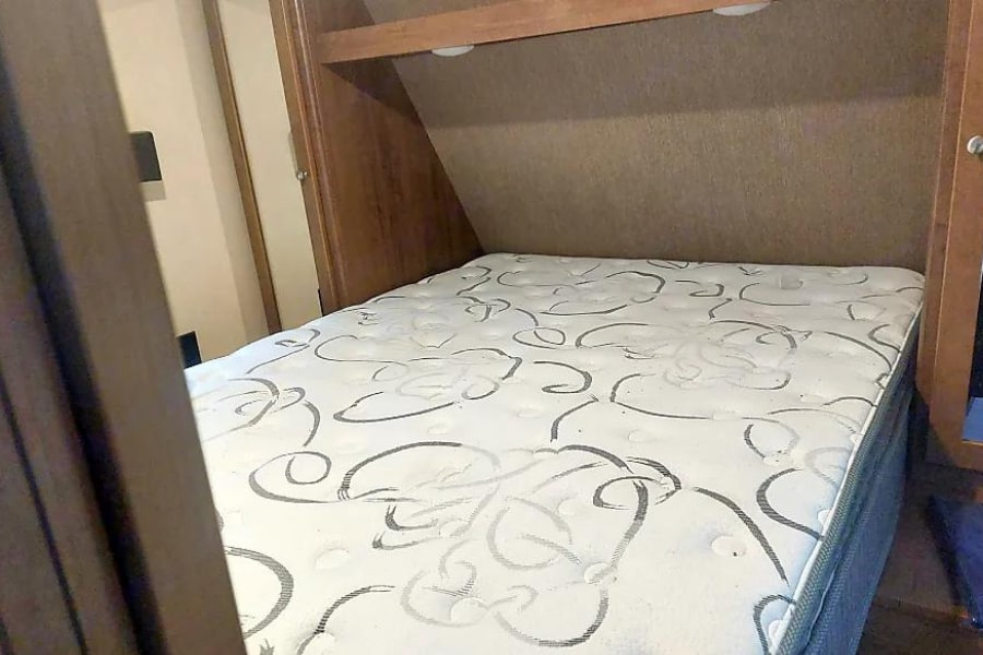 Cozy RV rental bed with a patterned mattress and overhead storage. Ready for your next adventure.. Dutchmen Aspen Trail 2017