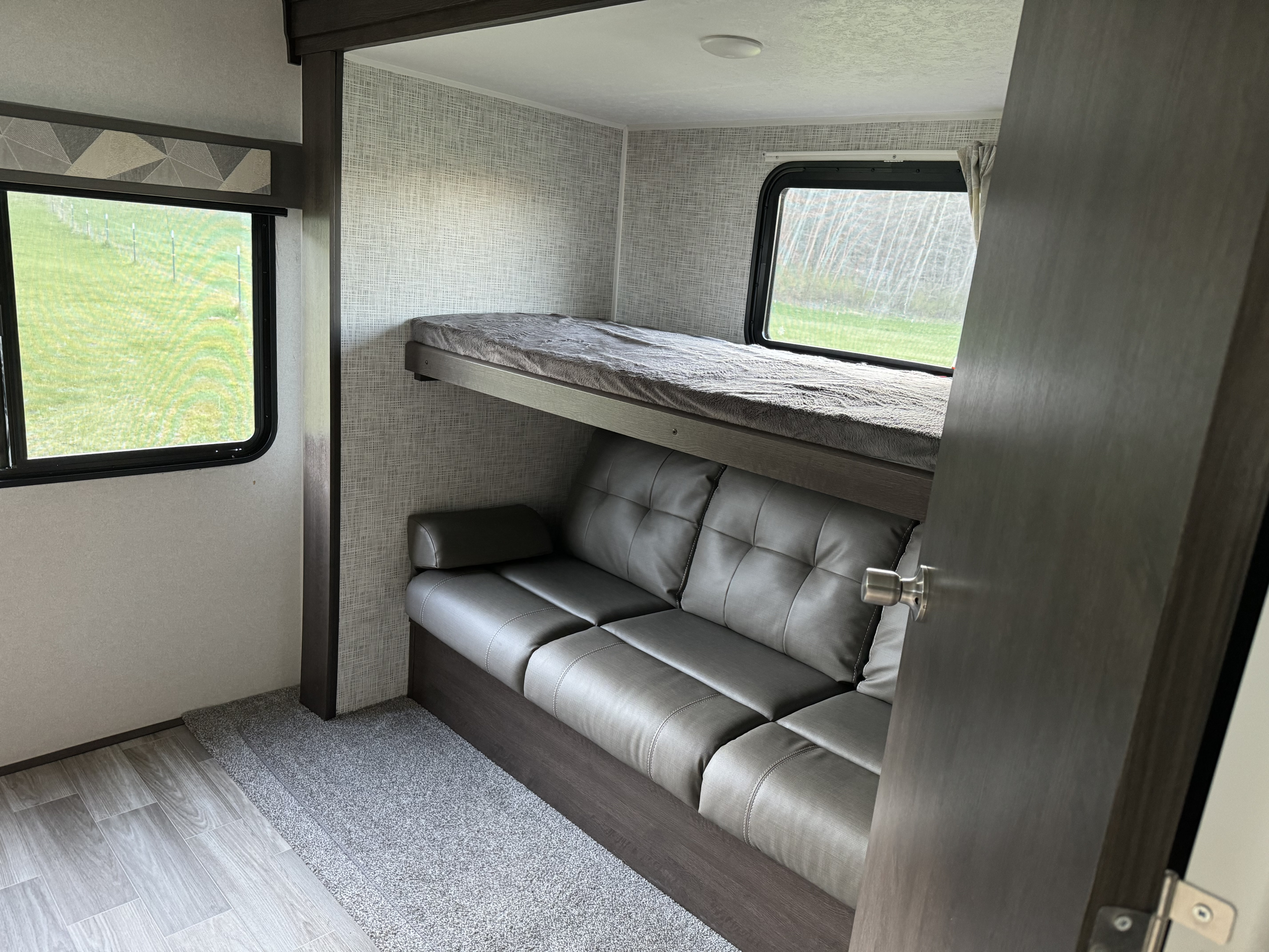 This RV rental offers a compact and functional interior with a modern sofa, an upper bunk bed, and scenic window views.. Forest River Salem 2020