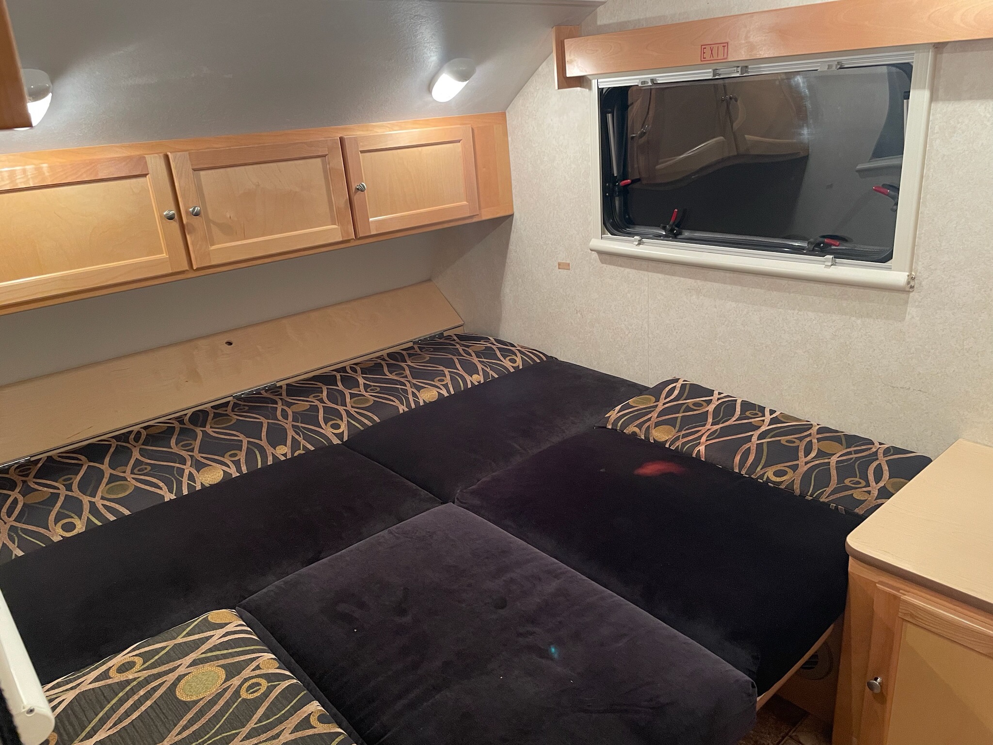 RV rental: Compact interior with a multi-cushion bed, overhead wood cabinets, and an exit window.. T@b Little Guy 2012