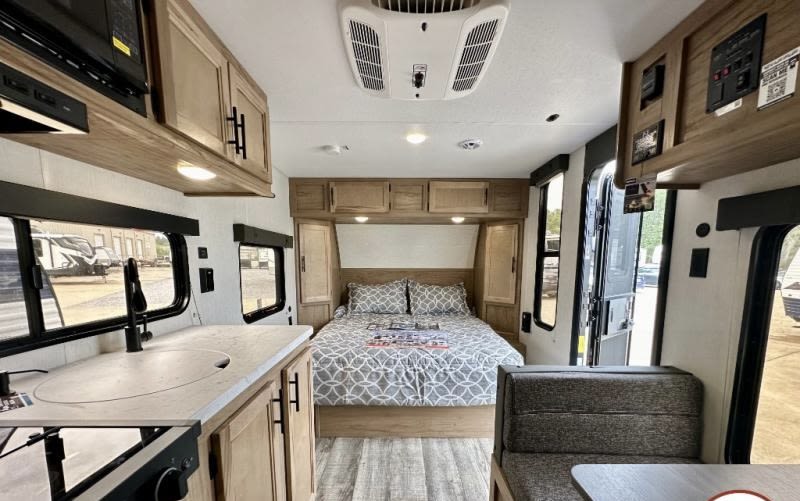 Inside a cozy RV rental, featuring a comfortable bedroom, compact kitchen, and dinette. Ideal for travel adventures.. Forest River Cherokee Wolf Pup 2023